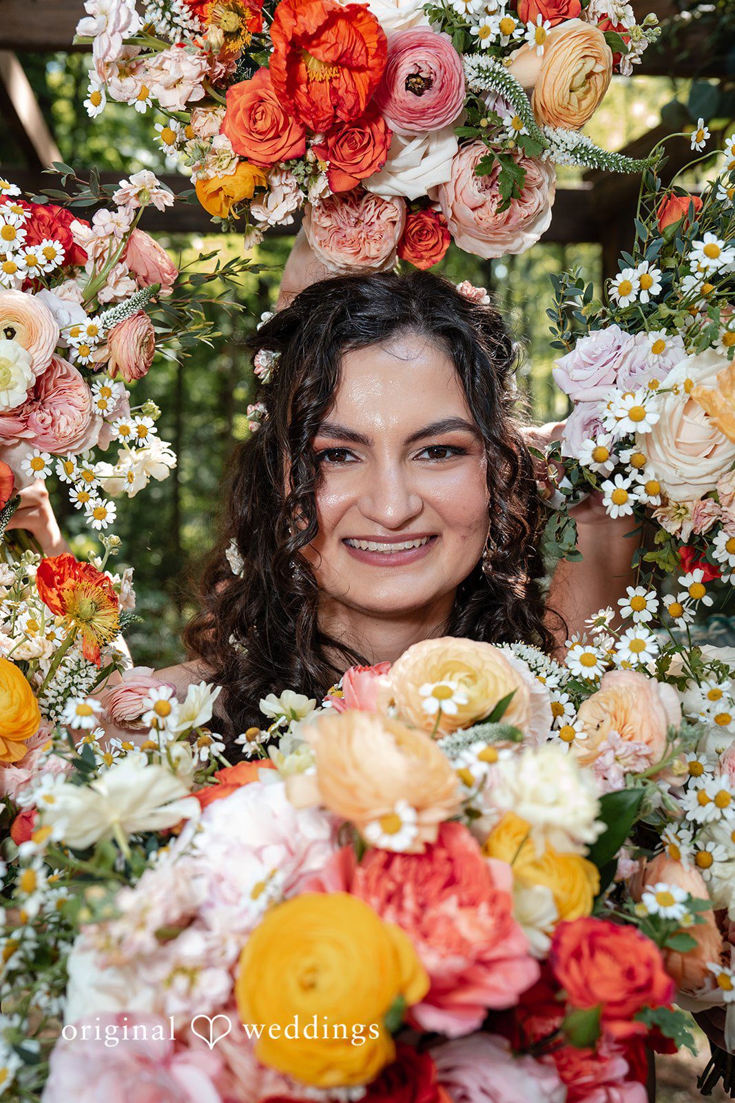 Conner + Ashley A close-up portrait of the bride smiling through a vibrant floral arrangement.