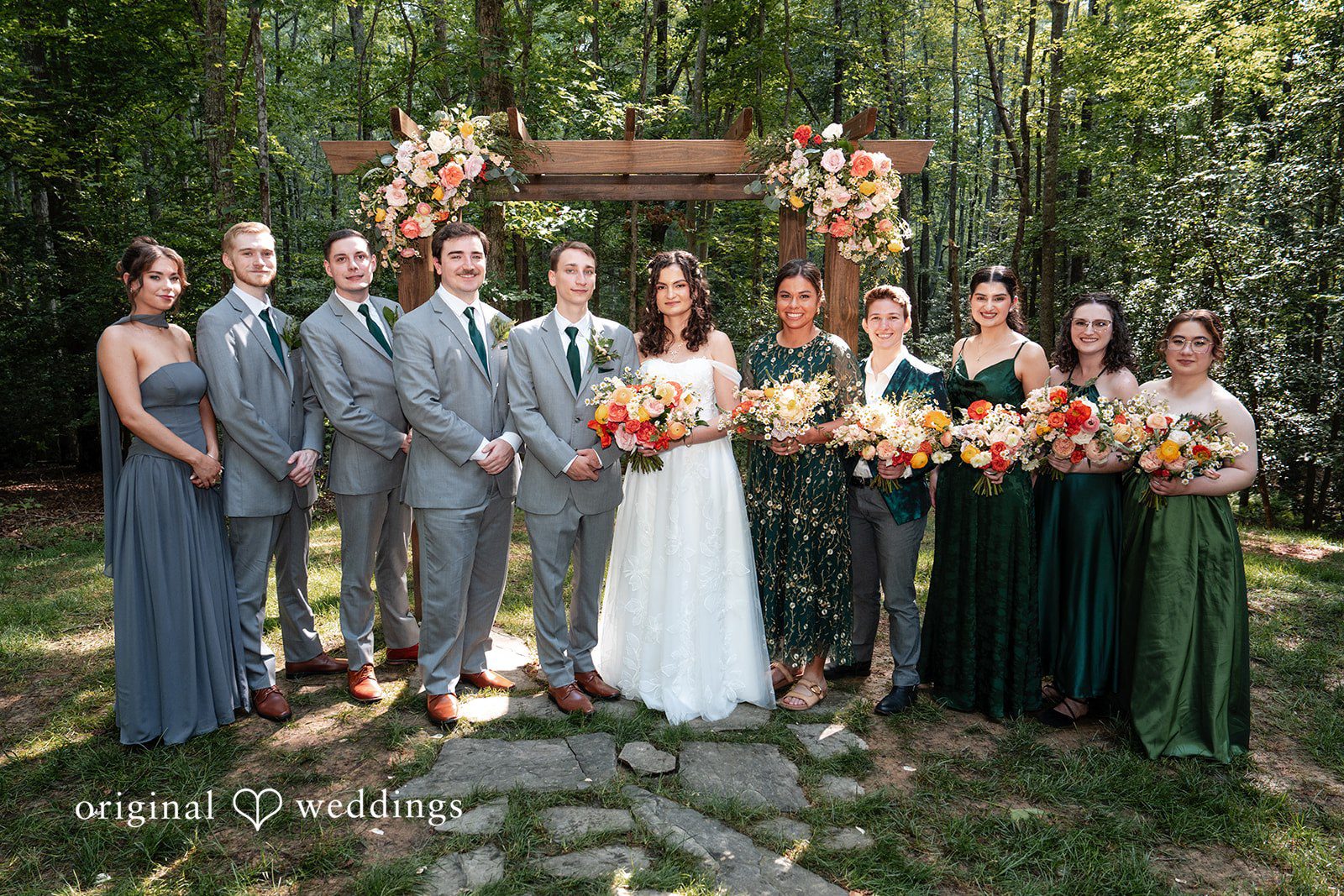 Conner + Ashley A full wedding party posing together in front of a wooden structure.