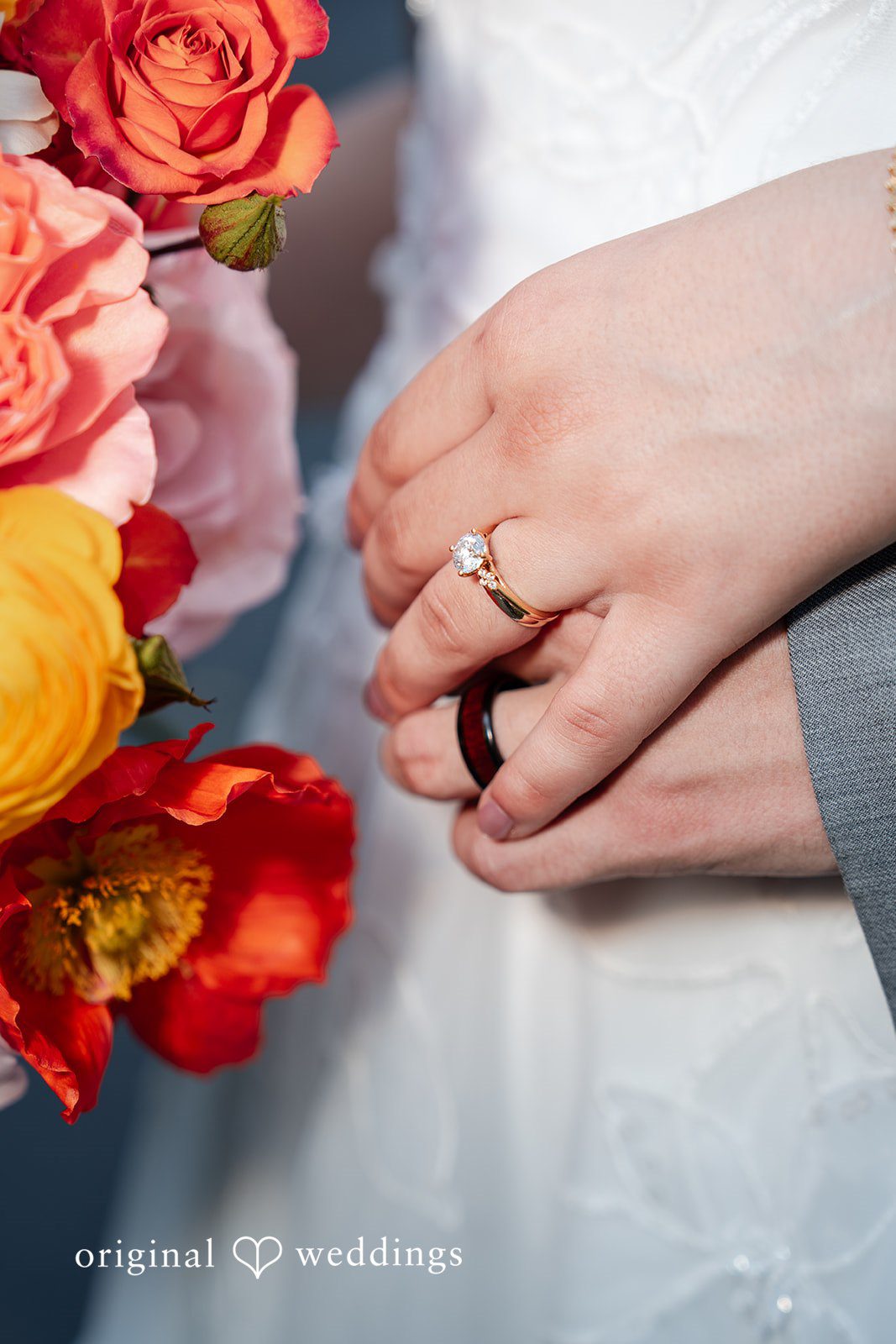 Conner + Ashley A close-up of a hand displaying an engagement ring over a wedding bouquet.