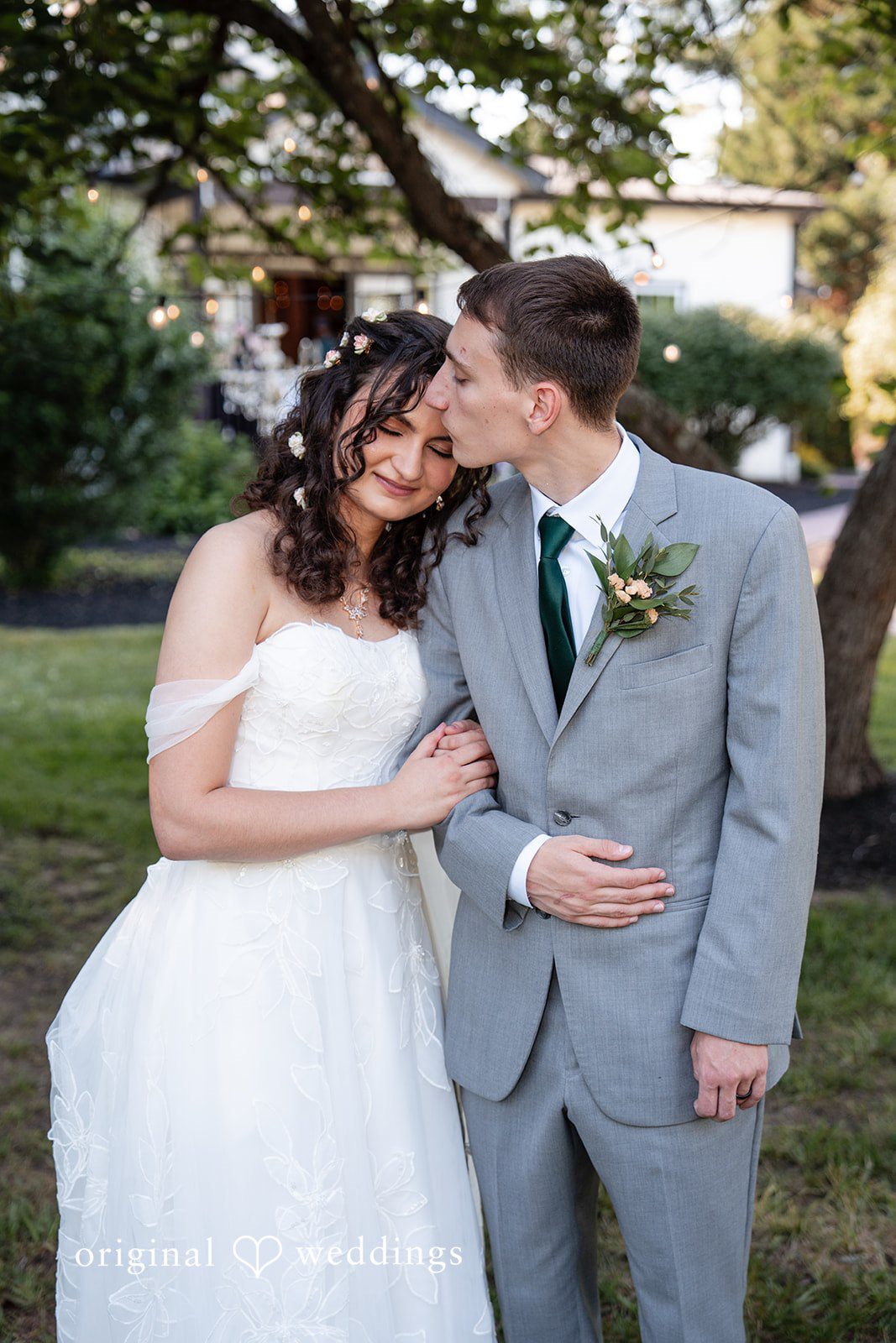 Conner + Ashley A bride and groom smiling and embracing closely on a lawn.