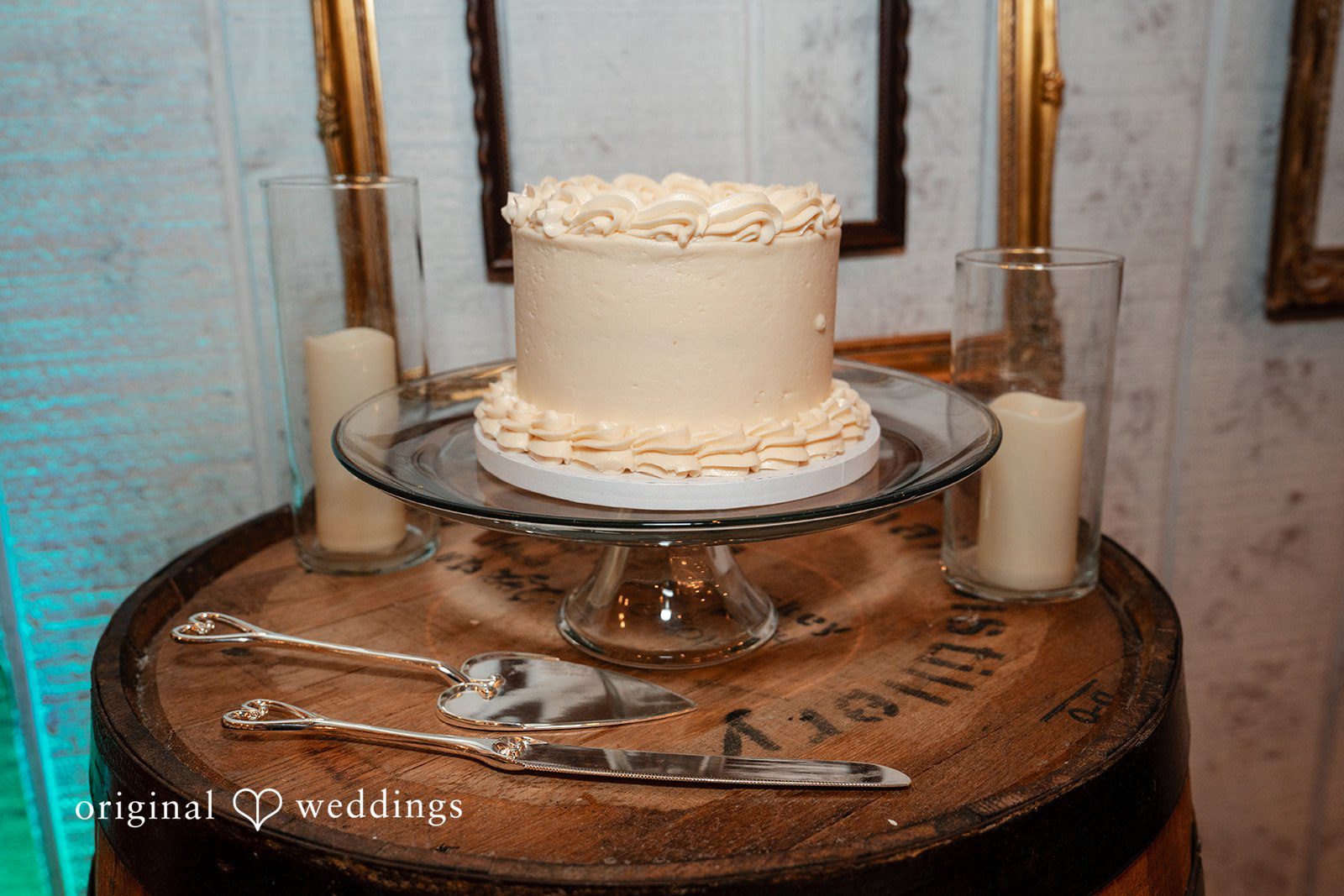 Conner + Ashley A single-tiered white frosted cake displayed on a wooden stand.