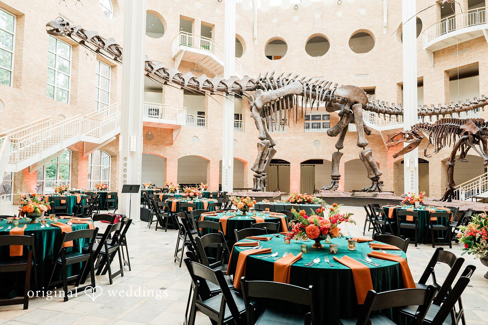 Sonya + Akshaya An event reception setup featuring round tables draped in dark tablecloths with colorful runners.
