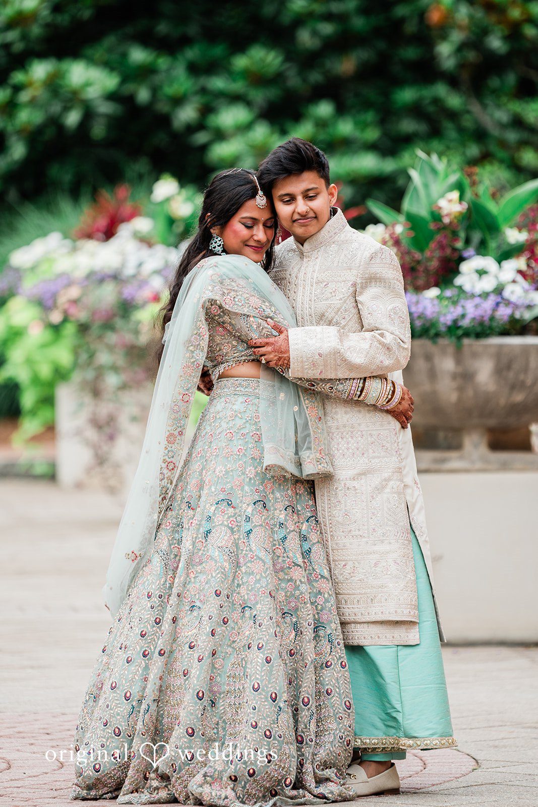 Sonya + Akshaya A groom wrapping his arms around the bride from behind as they smile.