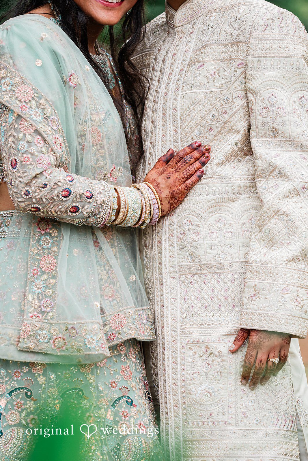 Sonya + Akshaya A close-up shot of a bride's hand resting gently on the groom's traditional sherwani.