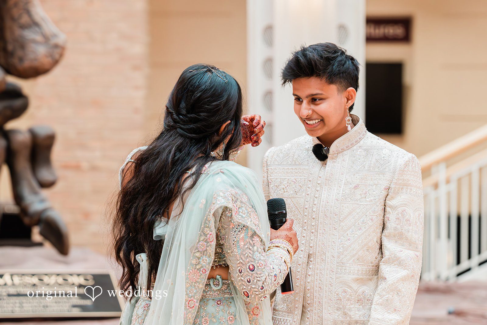 Sonya + Akshaya A bride with long dark hair smiling broadly while talking to the groom.