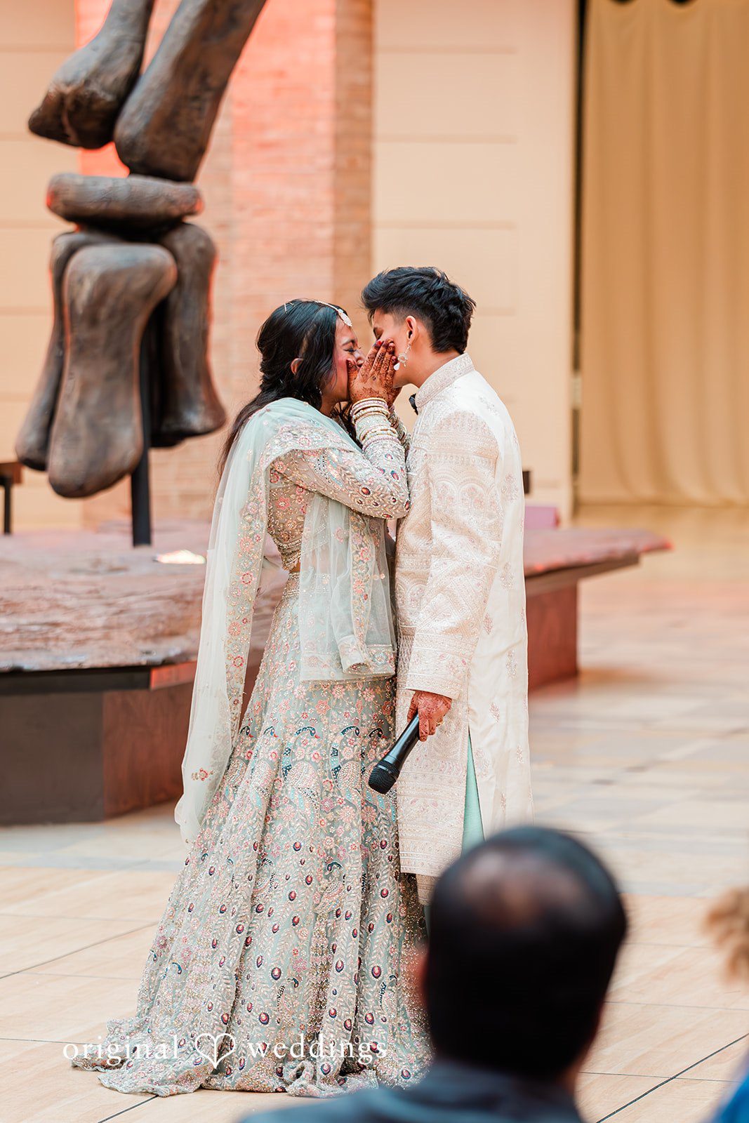 Sonya + Akshaya A bride and groom share a close, emotional moment standing on a stage during their wedding reception.