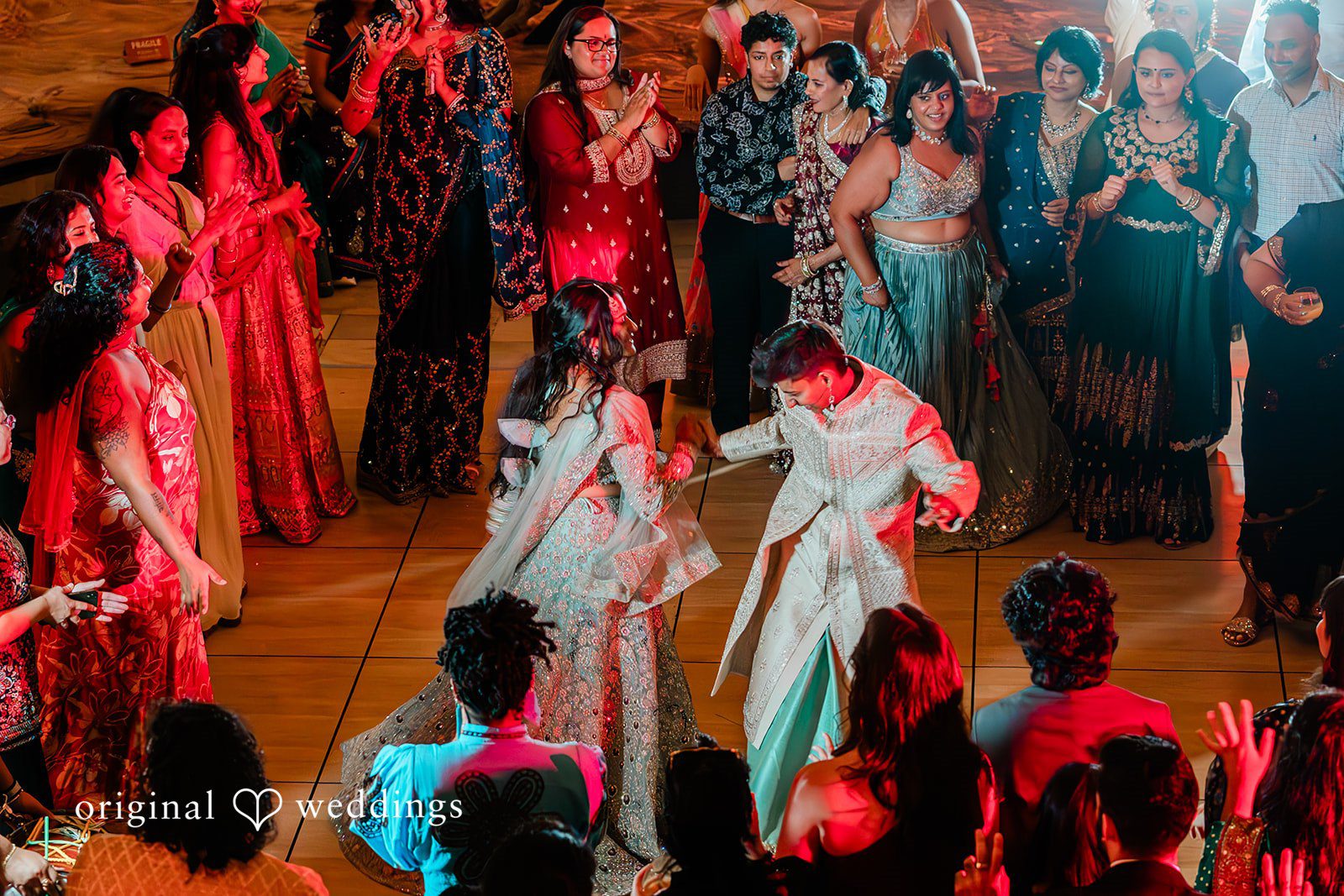 Sonya + Akshaya Wedding guests in colorful attire dance dynamically under vibrant party lighting.