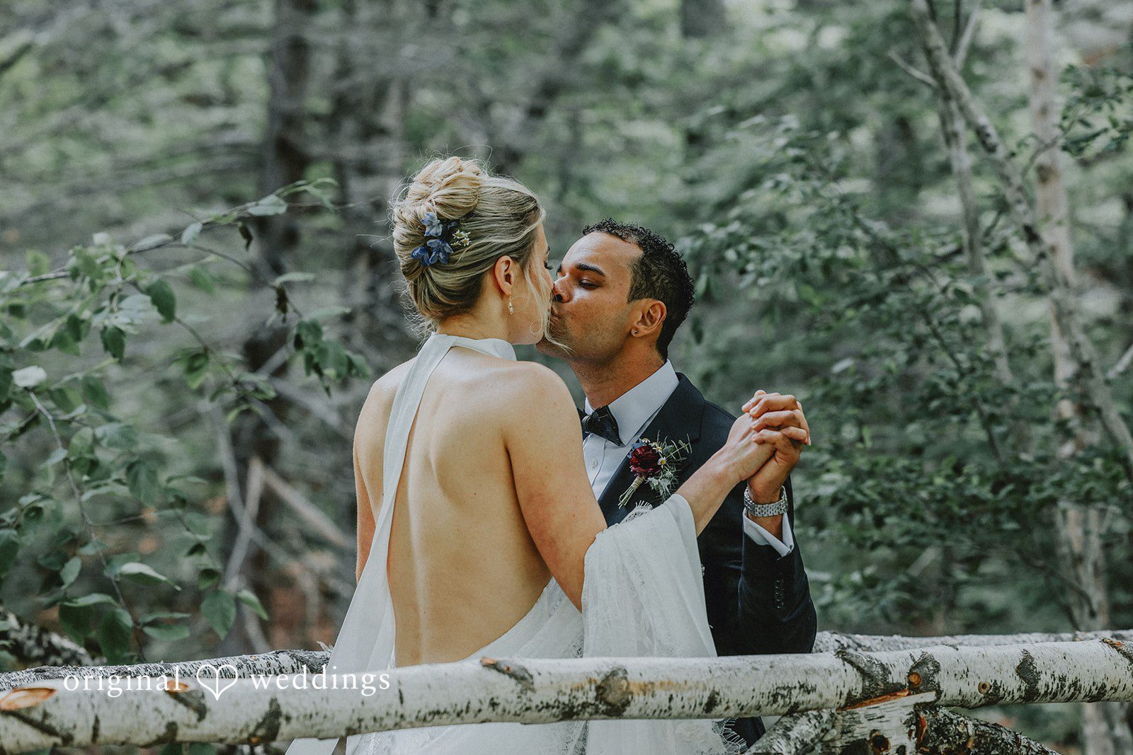 Bride and groom sharing a close embrace and smiling on a forest path.