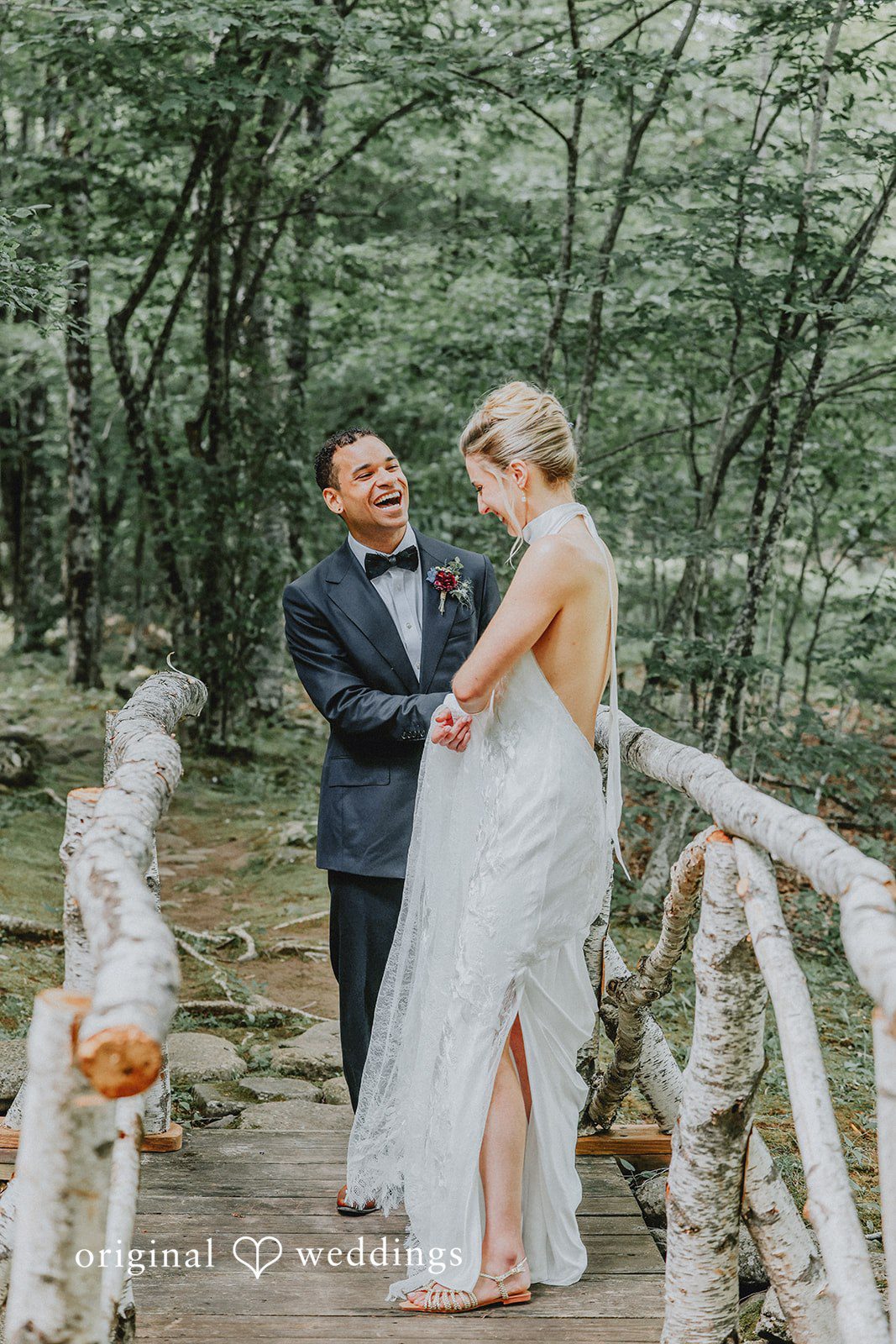 Groom holding the bride as she laughs on a bridge.