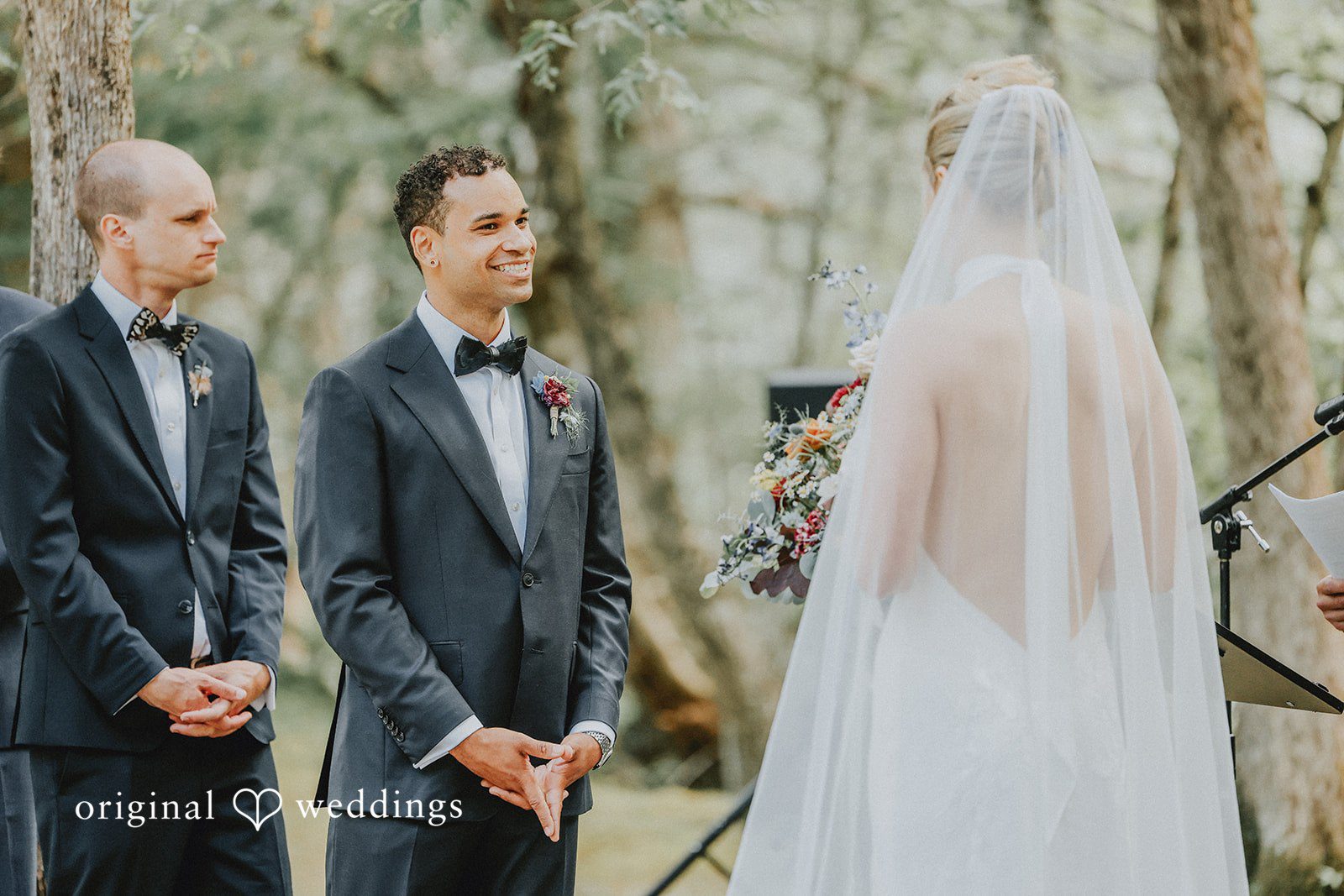 Rear view of a bride with a long veil facing the groom during the ceremony.