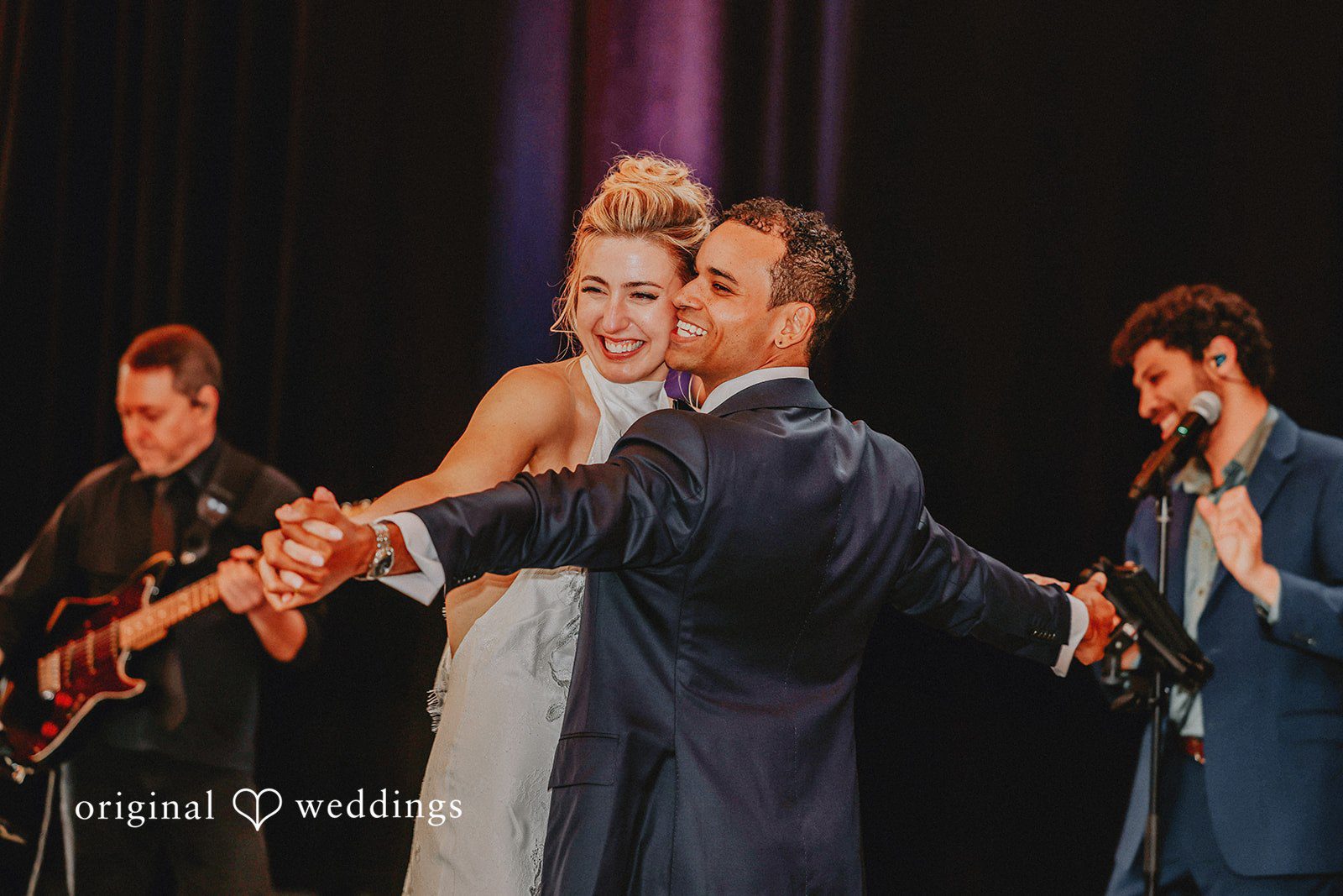 Groom leading the bride onto the dance floor during a lively reception dance.