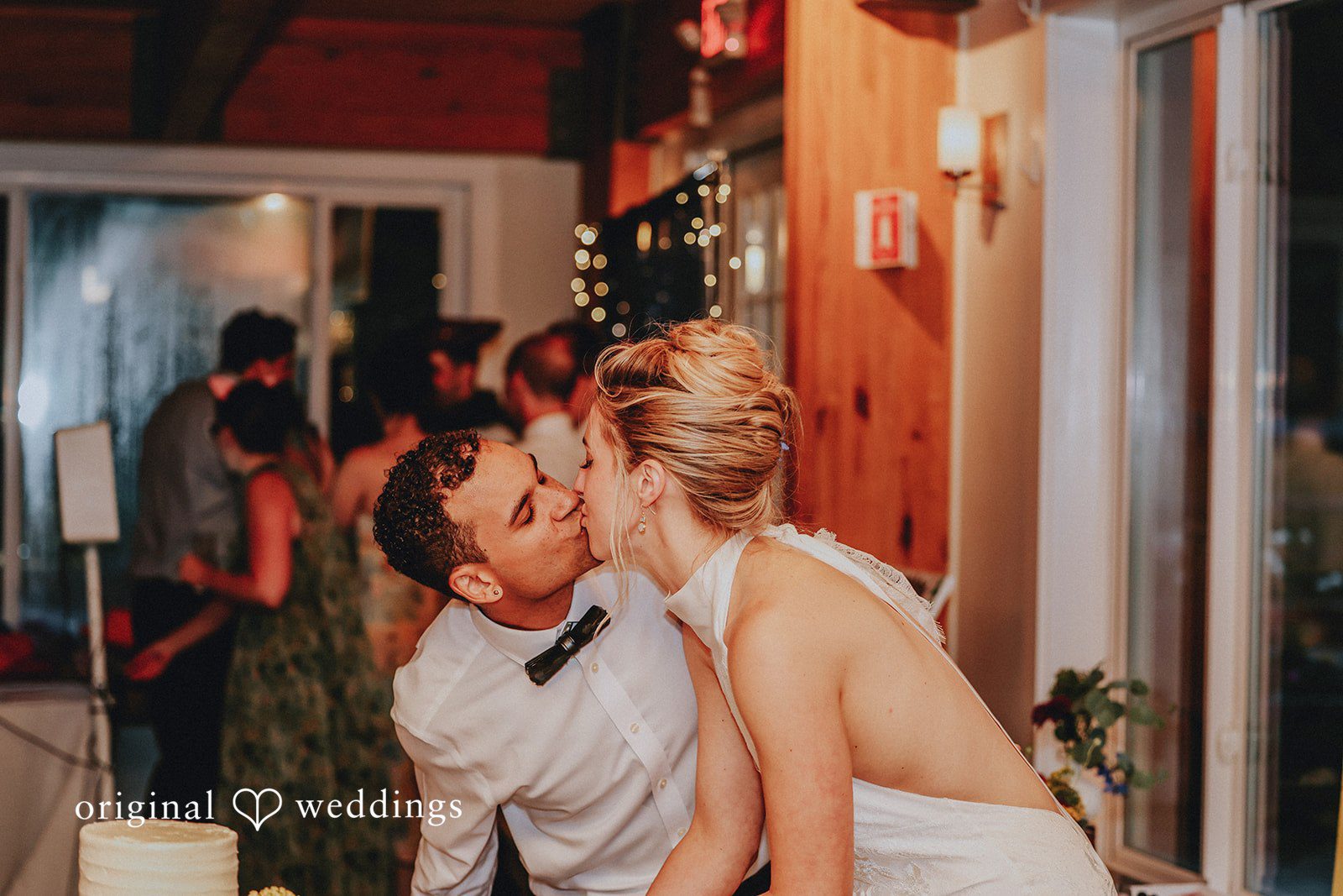 Bride leaning down to share a sweet kiss with the groom at a table.