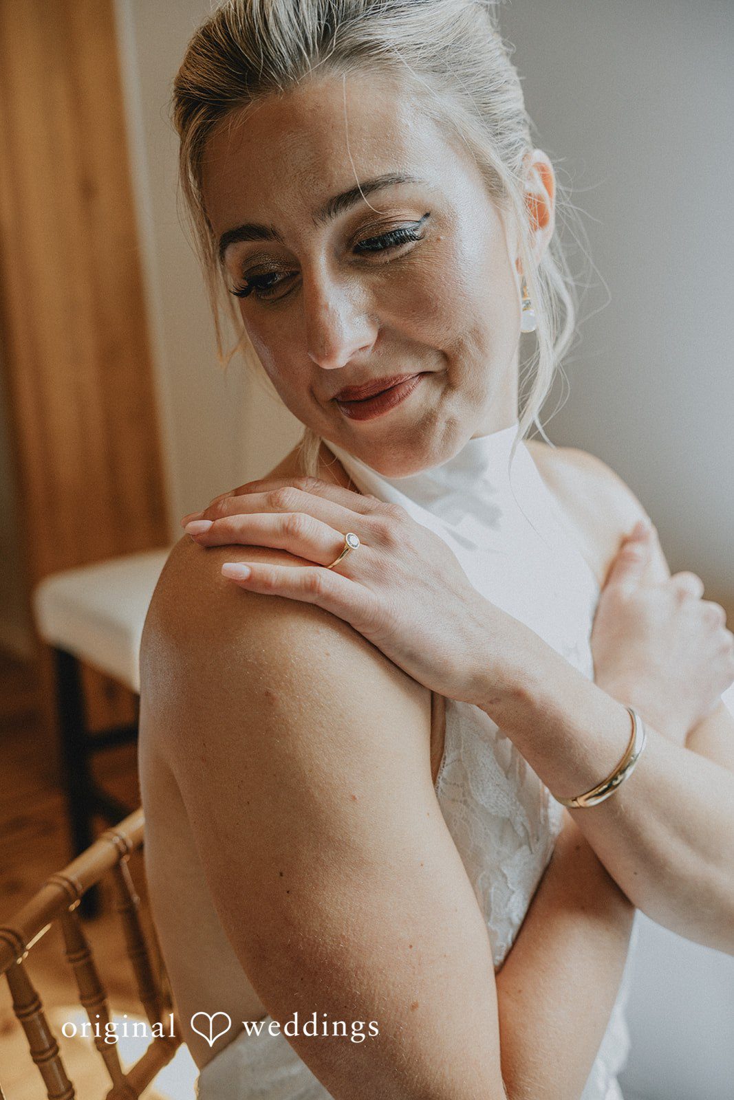 Close-up portrait of a smiling bride looking down over her shoulder.