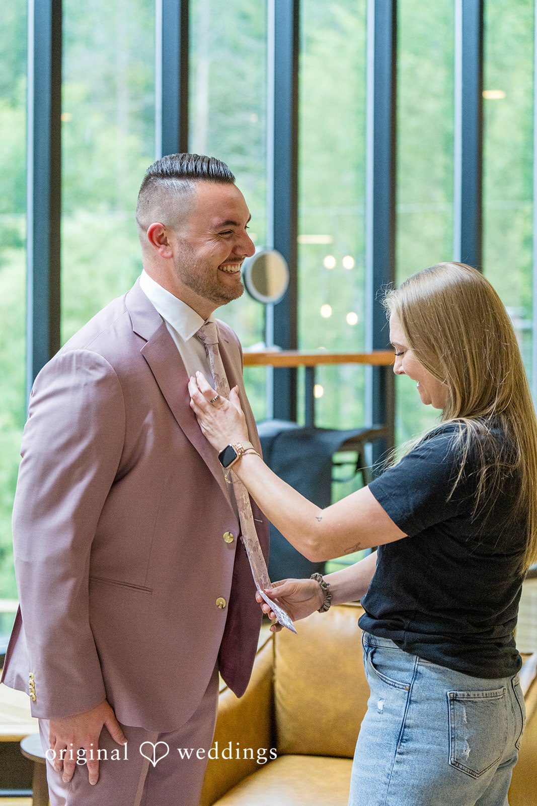 Kristian + Jeff A woman adjusting the lapel of a man wearing a mauve suit.