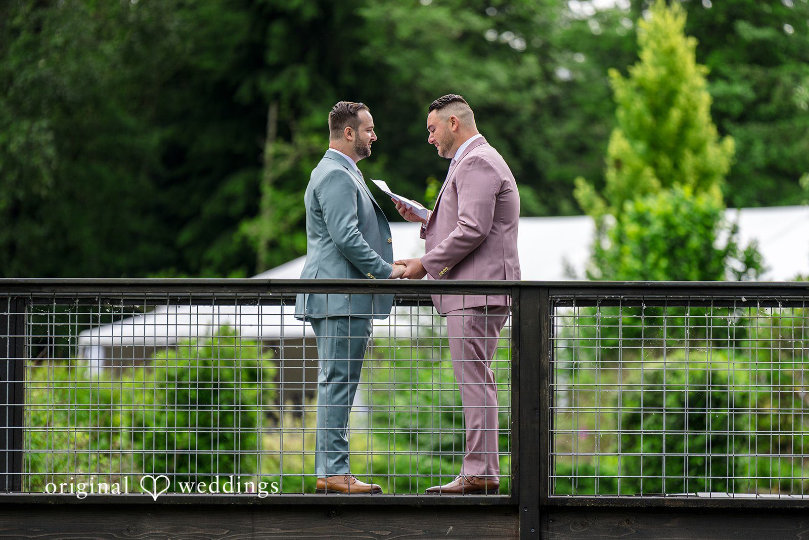 Kristian + Jeff Couple holding hands and facing each other on a bridge walkway.
