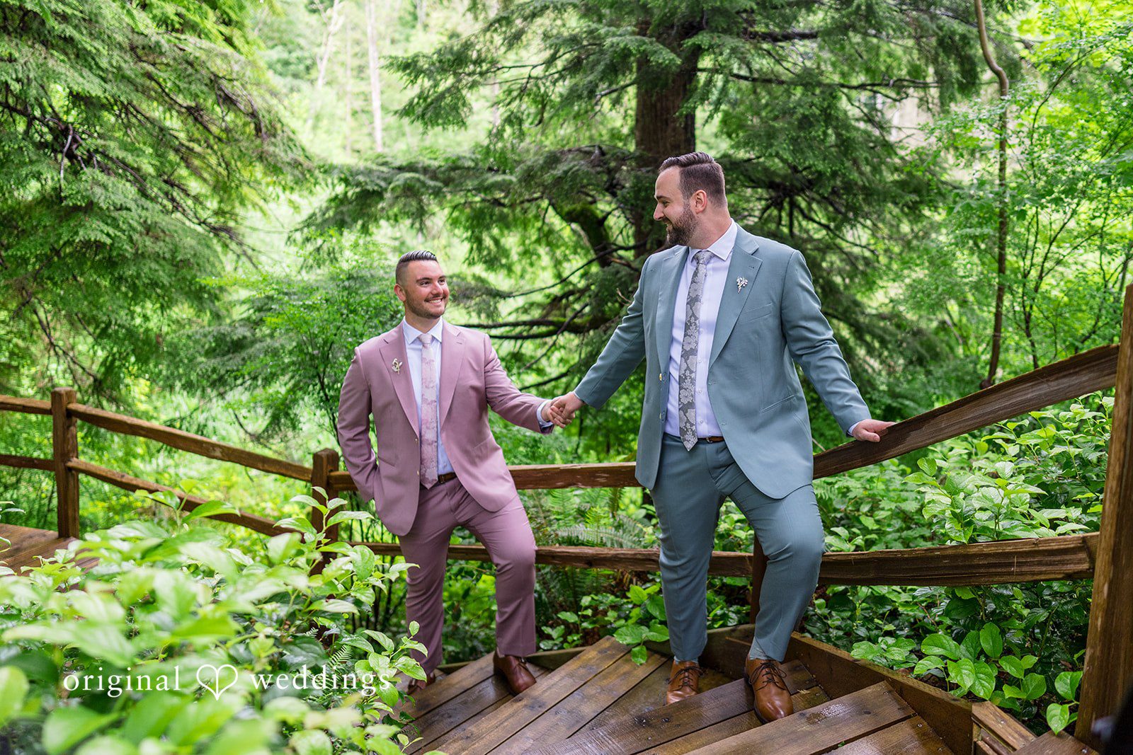 Kristian + Jeff Couple holding hands while walking down a set of wooden steps surrounded by trees.