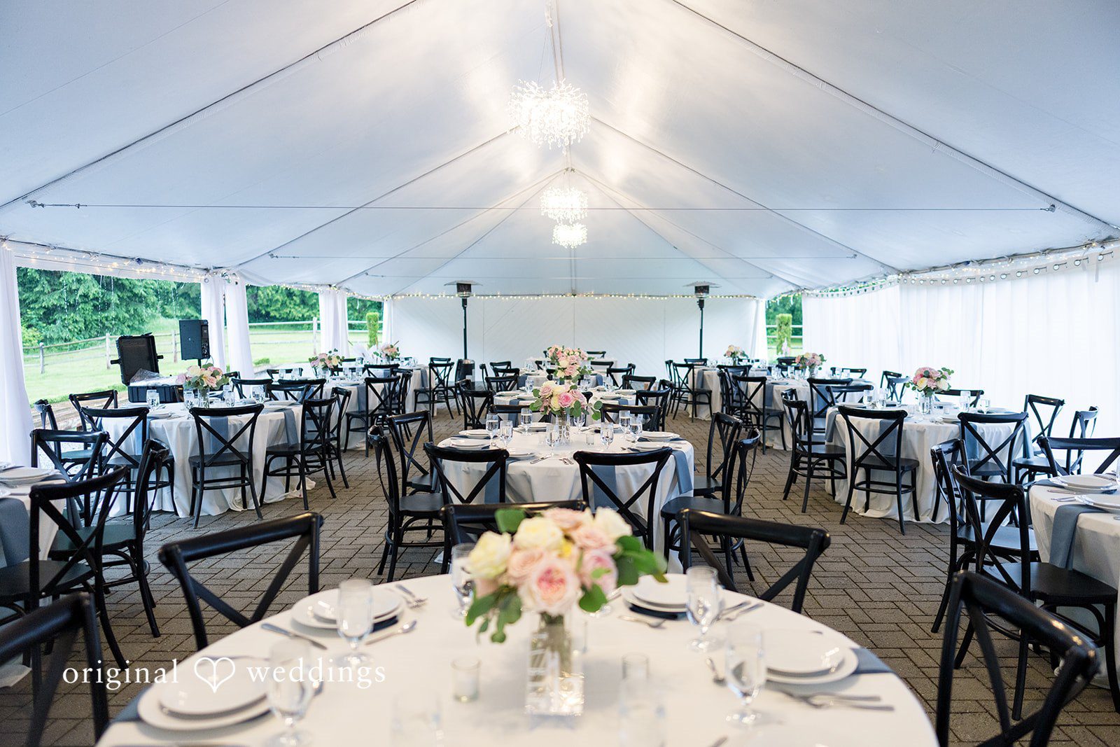 Kristian + Jeff View inside a large white event tent filled with decorated reception tables and floral centerpieces.