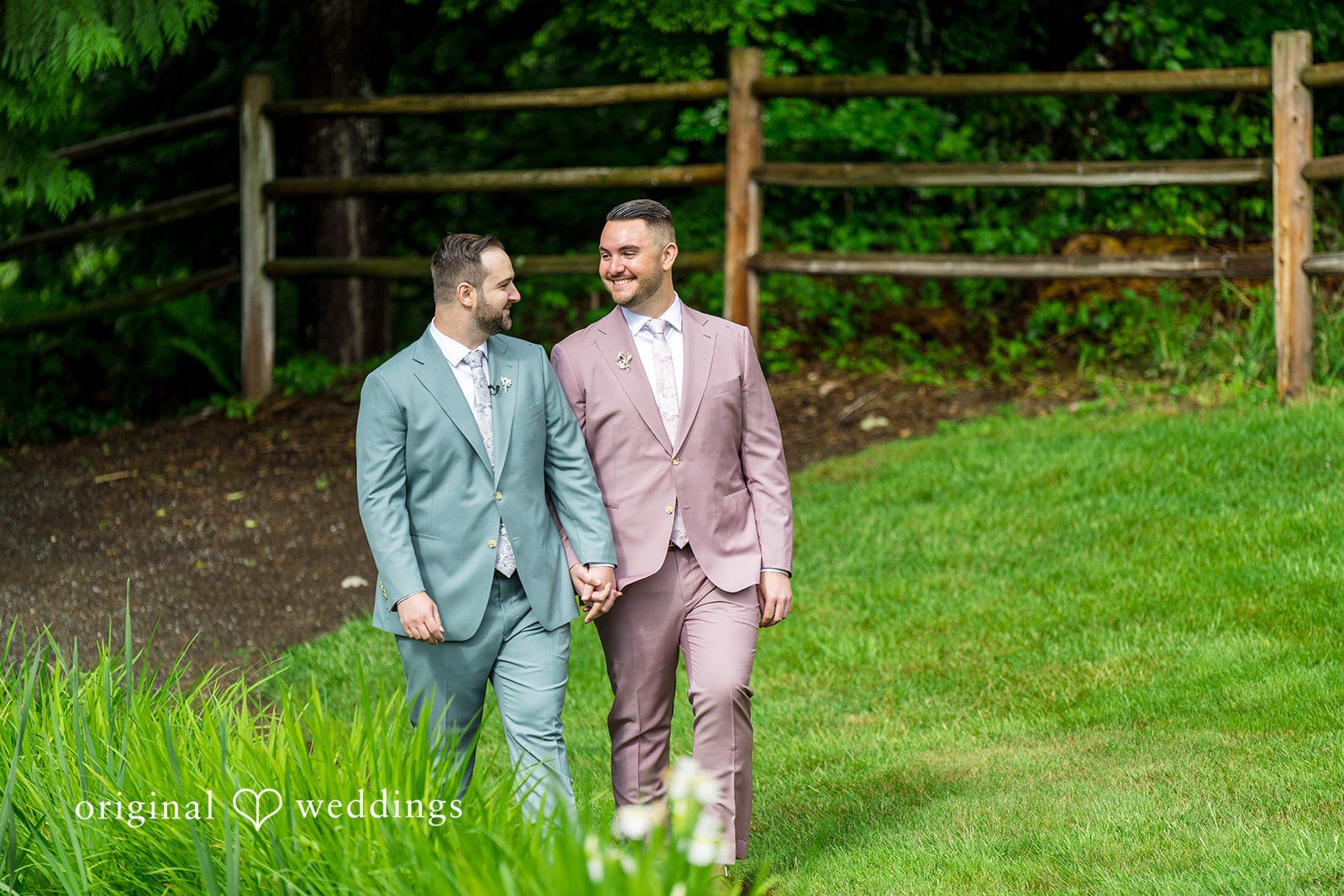 Kristian + Jeff Couple holding hands and smiling while walking together on a green grassy lawn.