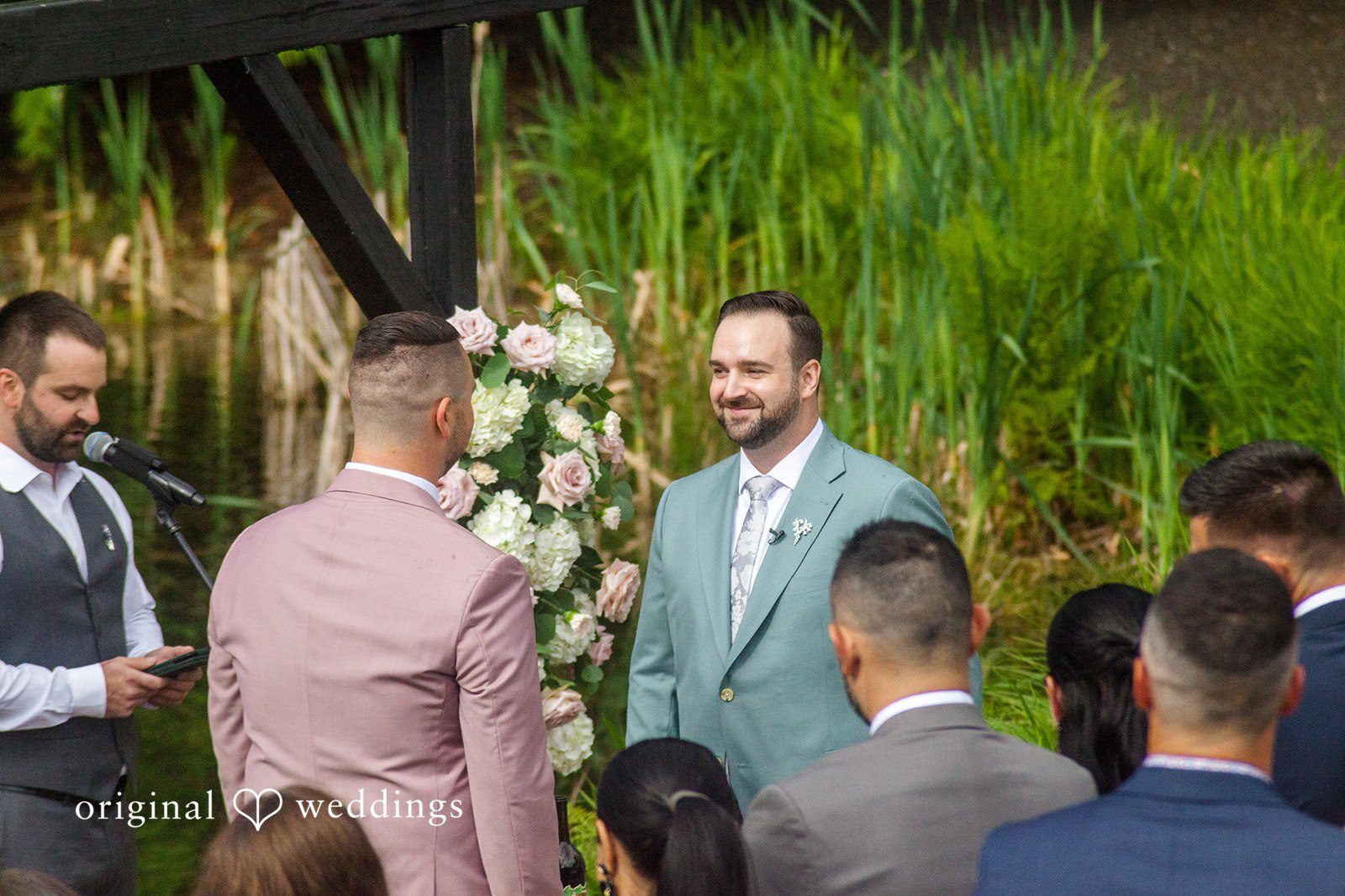 Kristian + Jeff A groom in a light blue suit smiling at his partner during the wedding ceremony.