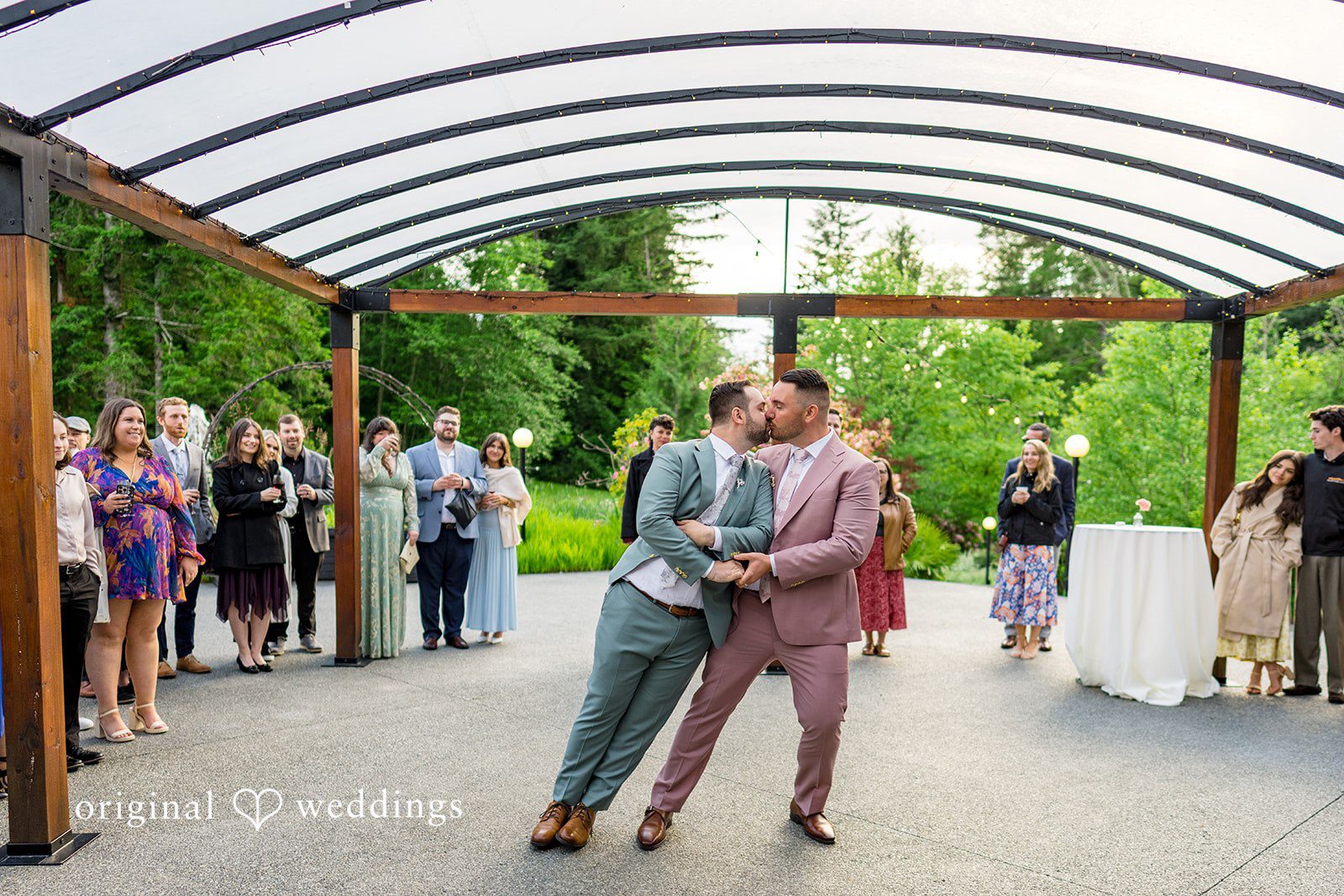 Kristian + Jeff One groom dipping the other groom during their first dance under a covered outdoor pavilion.
