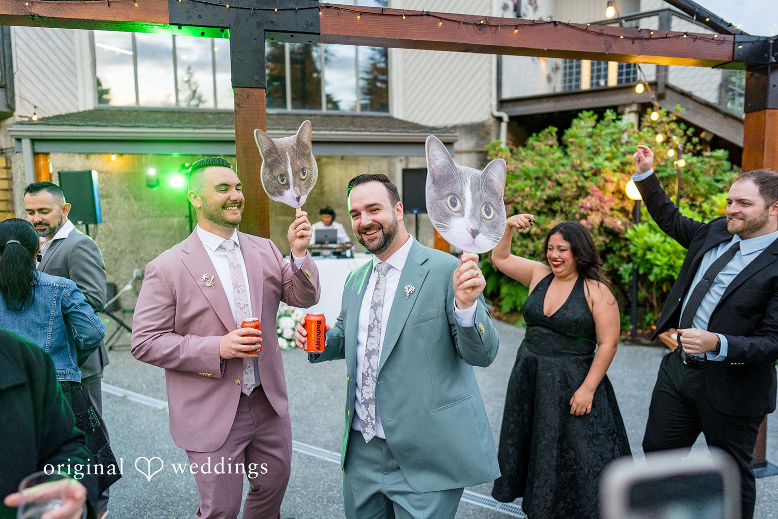 Kristian + Jeff Couple holding up large oversized wine glasses and smiling during the reception.