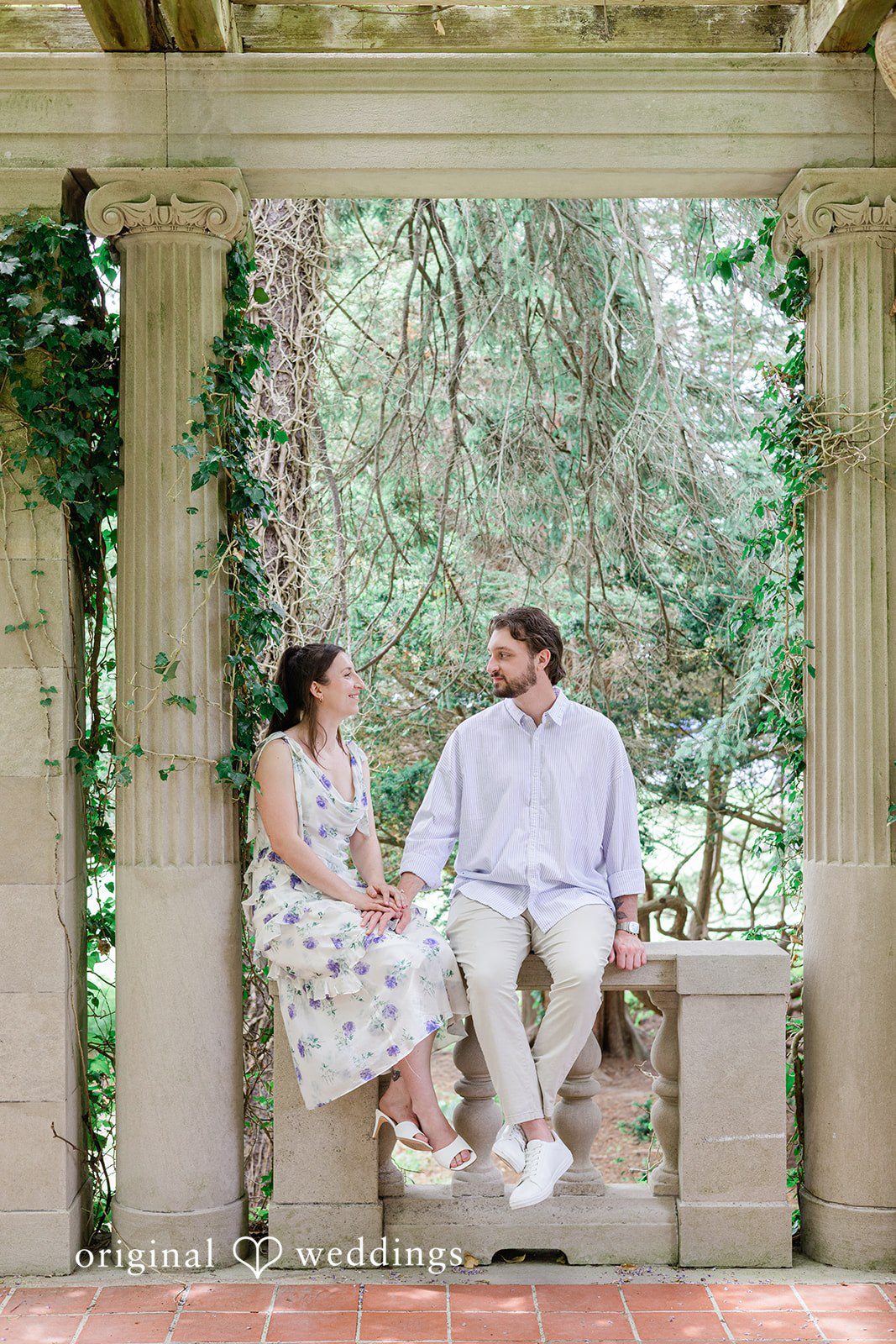 Couple smiling while sitting on a wall and looking each other at Harkness Park
