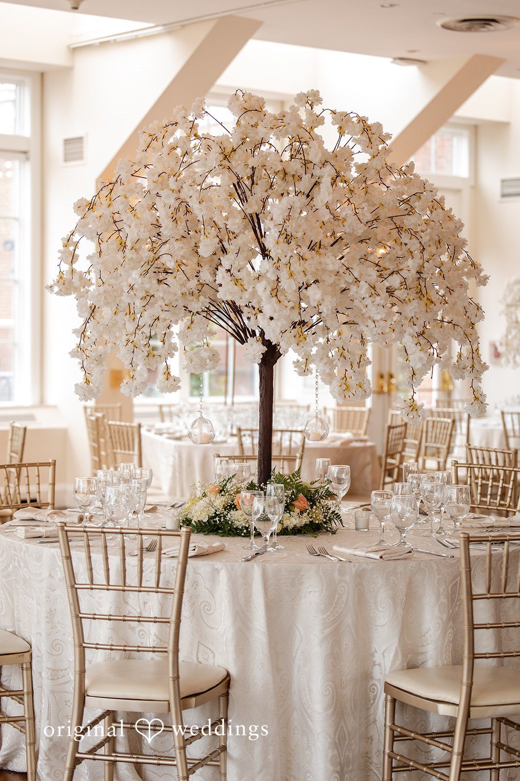 Round reception table featuring a large, white faux blossom tree centerpiece.