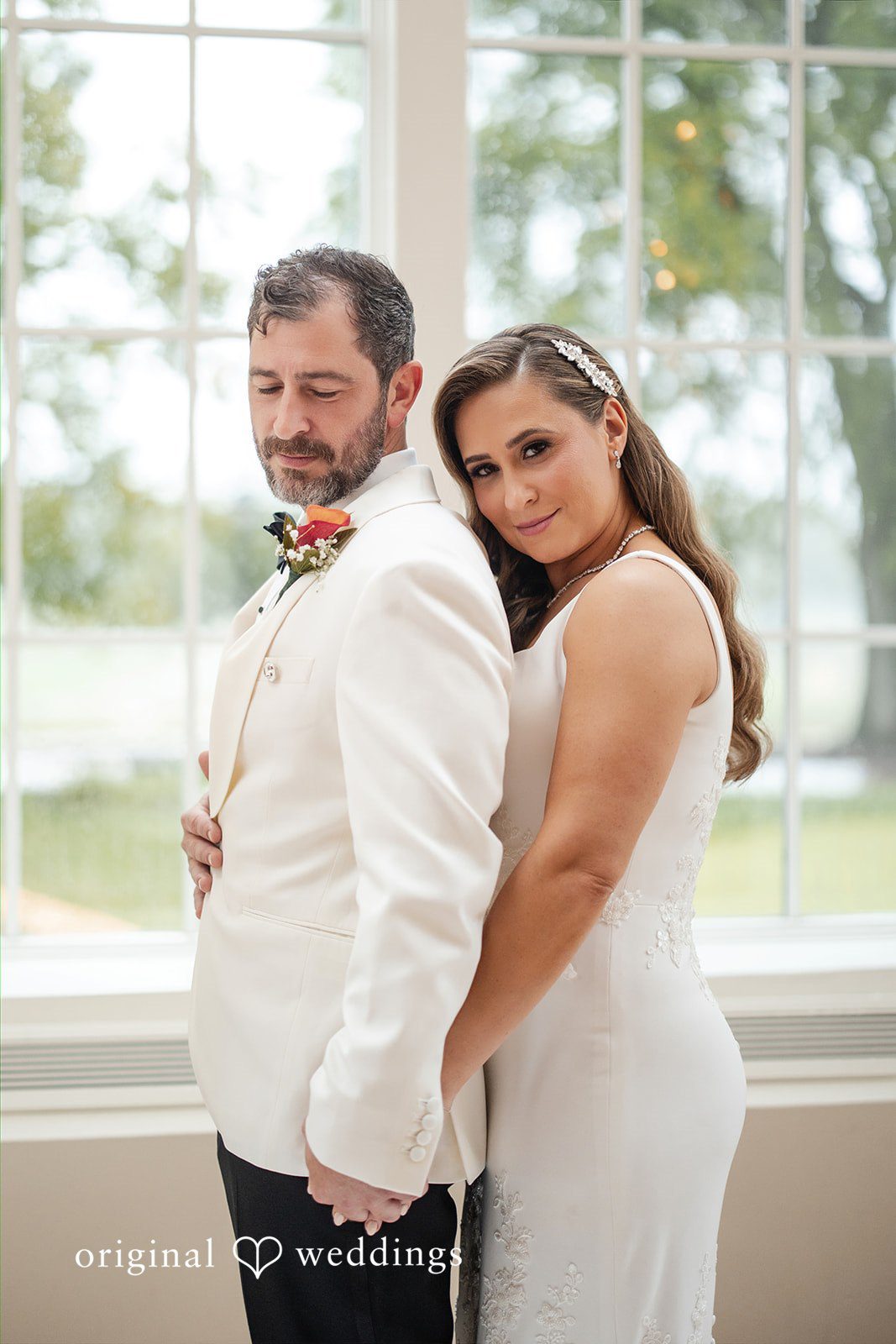 Bride hugging the groom from behind while both smile softly for a portrait.