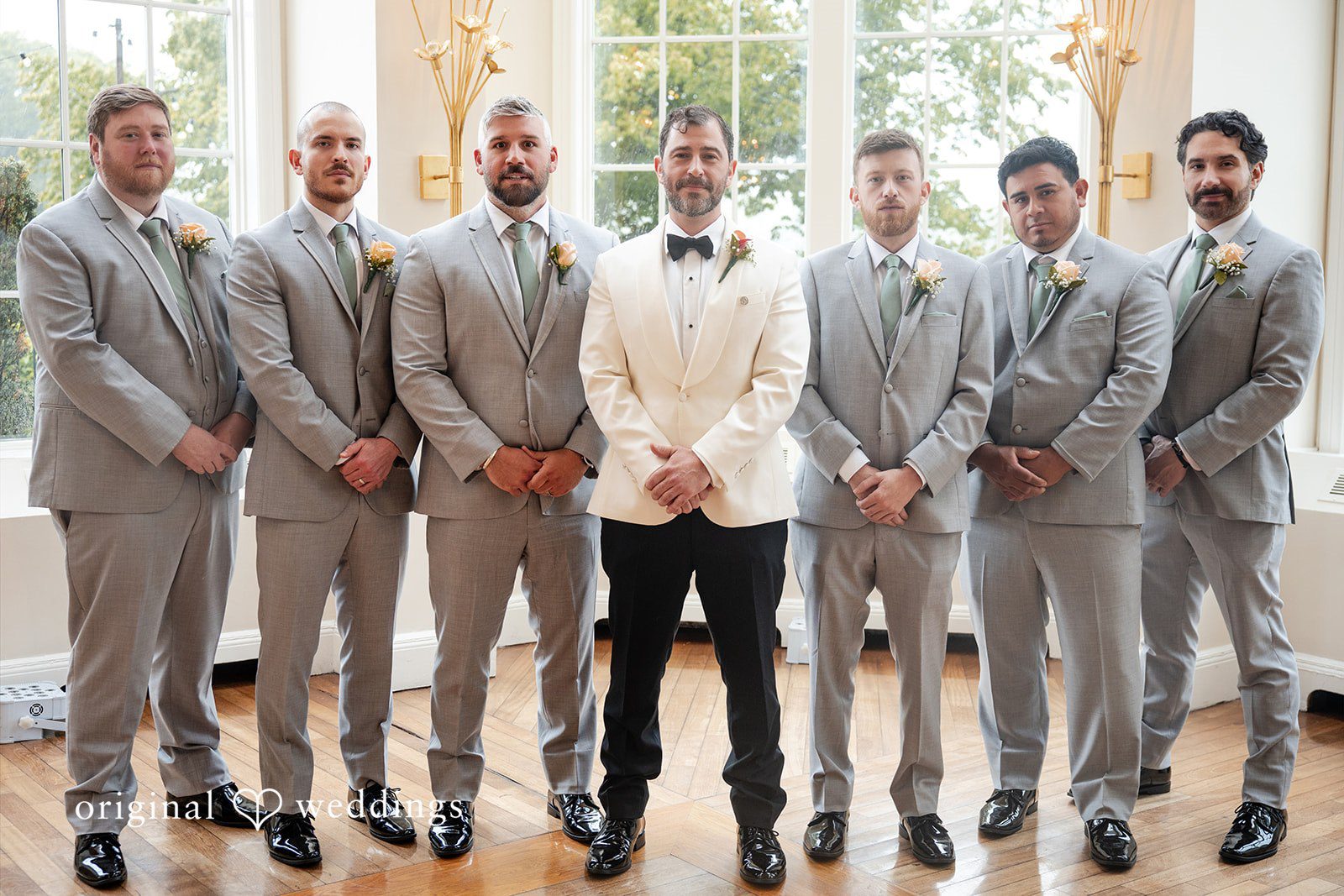 Groom standing with a line of groomsmen in matching grey suits.