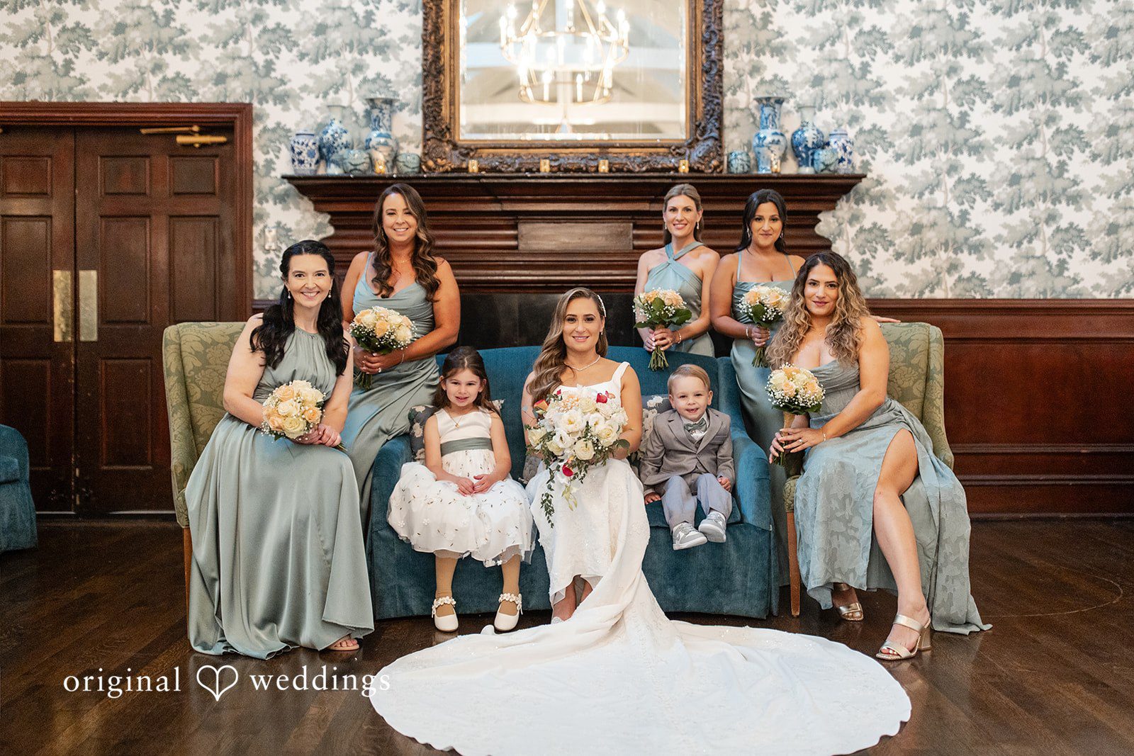Bride posing with her bridesmaids sitting around her on chairs.