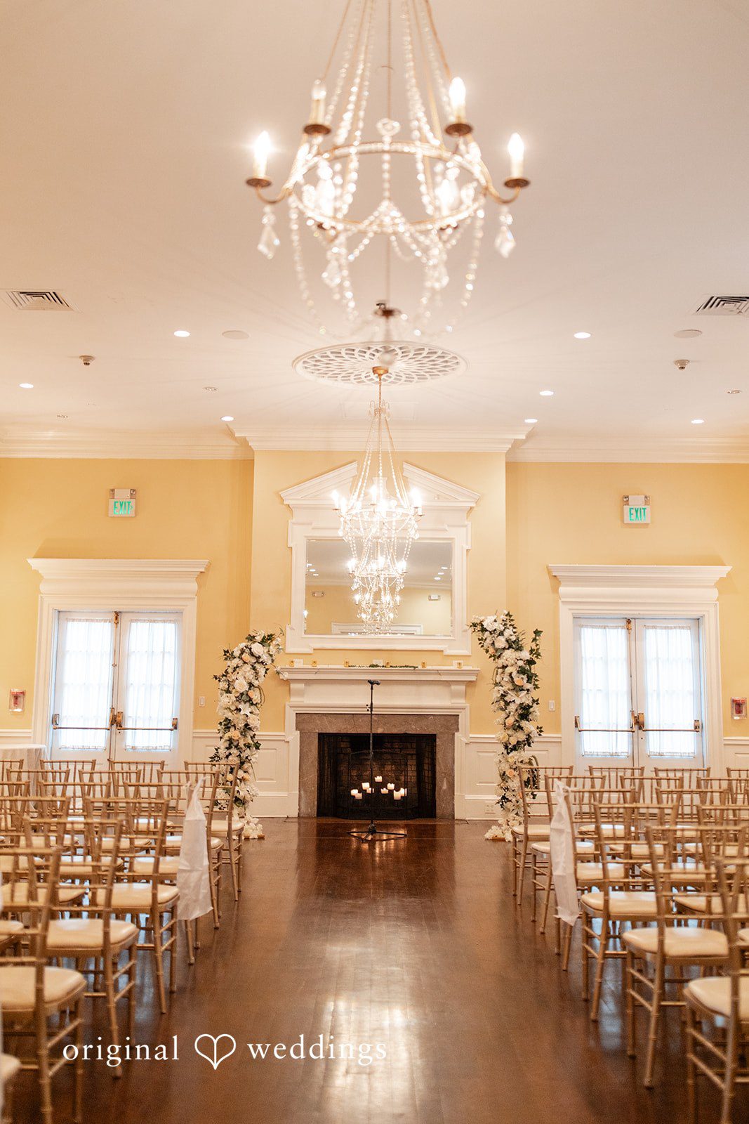 Empty wedding ceremony room with rows of wooden chairs facing a fireplace.
