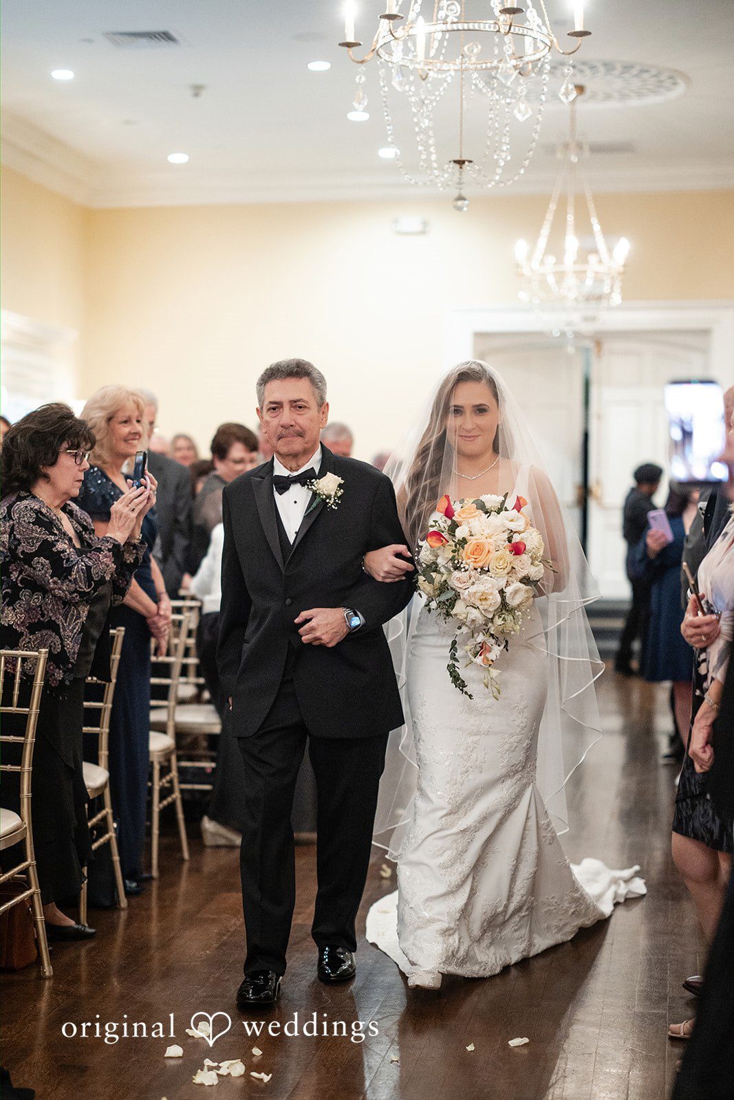 Bride and man walking down the aisle while wedding guests applaud.