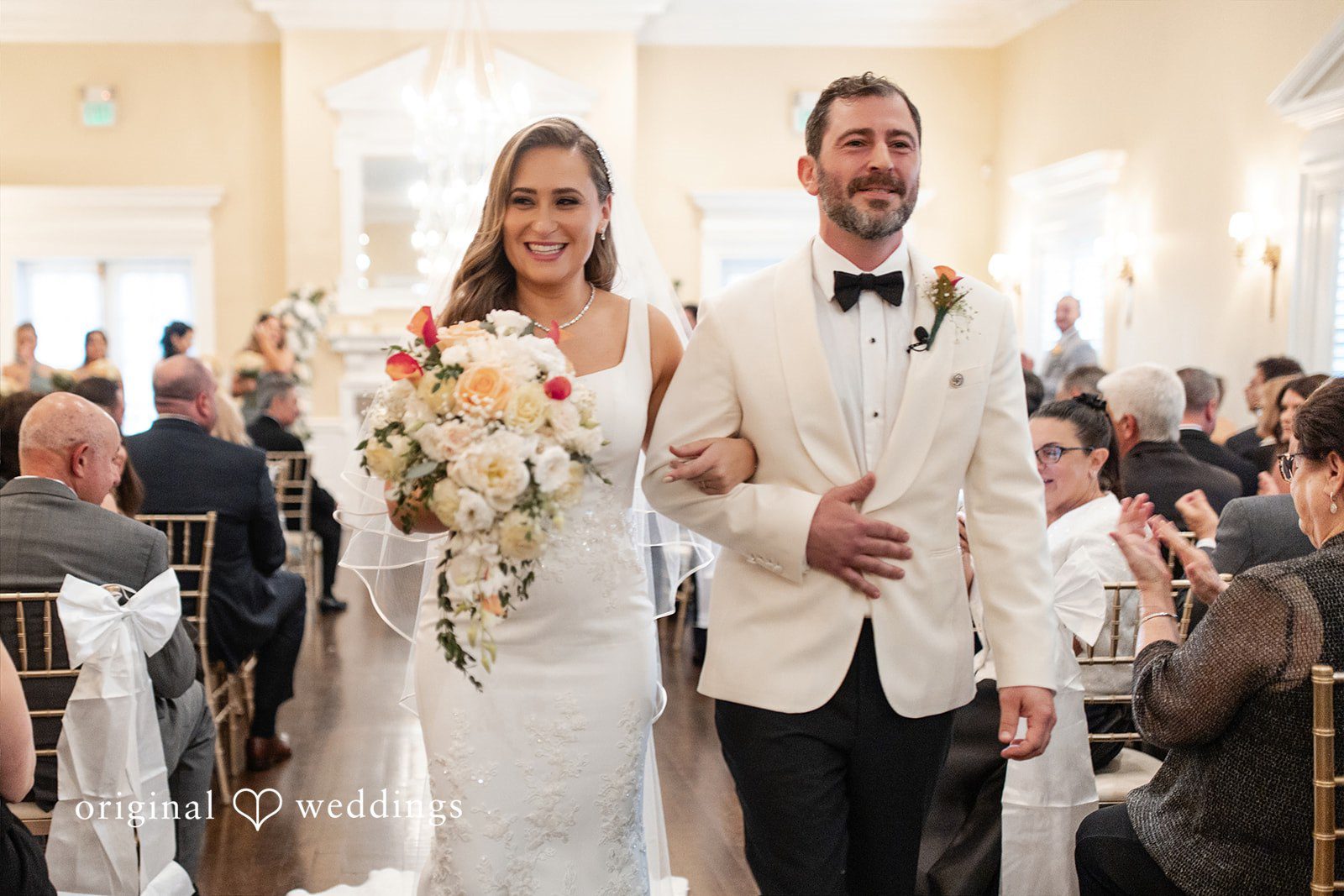 Newlyweds smiling and walking together down the aisle after their ceremony.