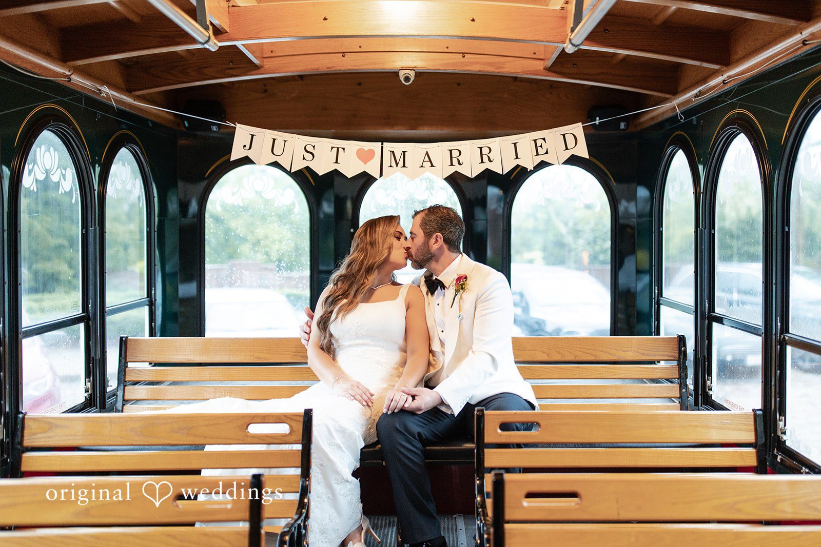 Bride and groom sitting together on a wooden bench.