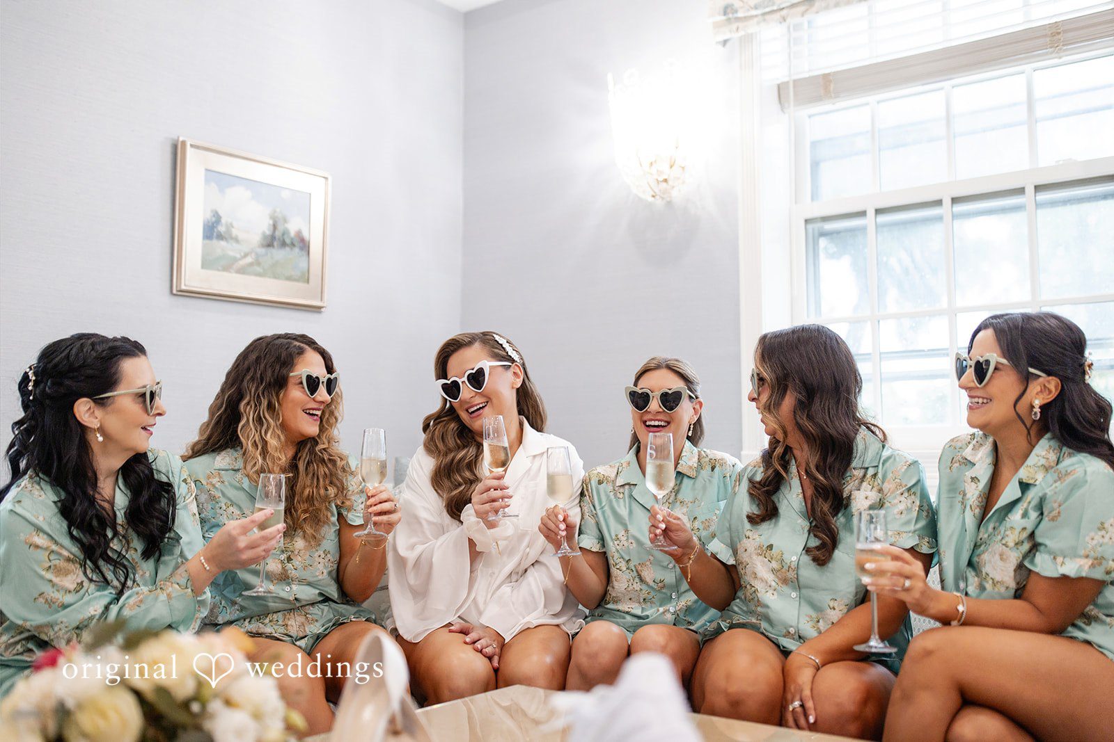 Bridesmaids in matching green shirts sitting together on a couch.