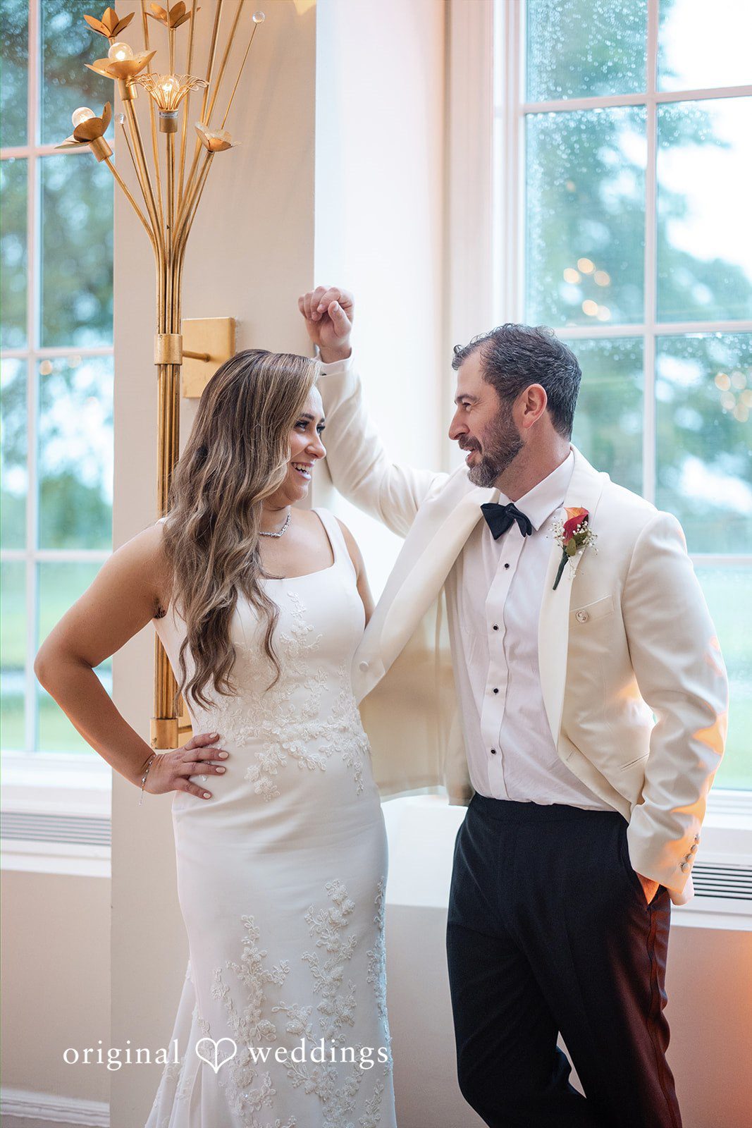 Bride and groom playfully posing and raising their hands together during portraits.
