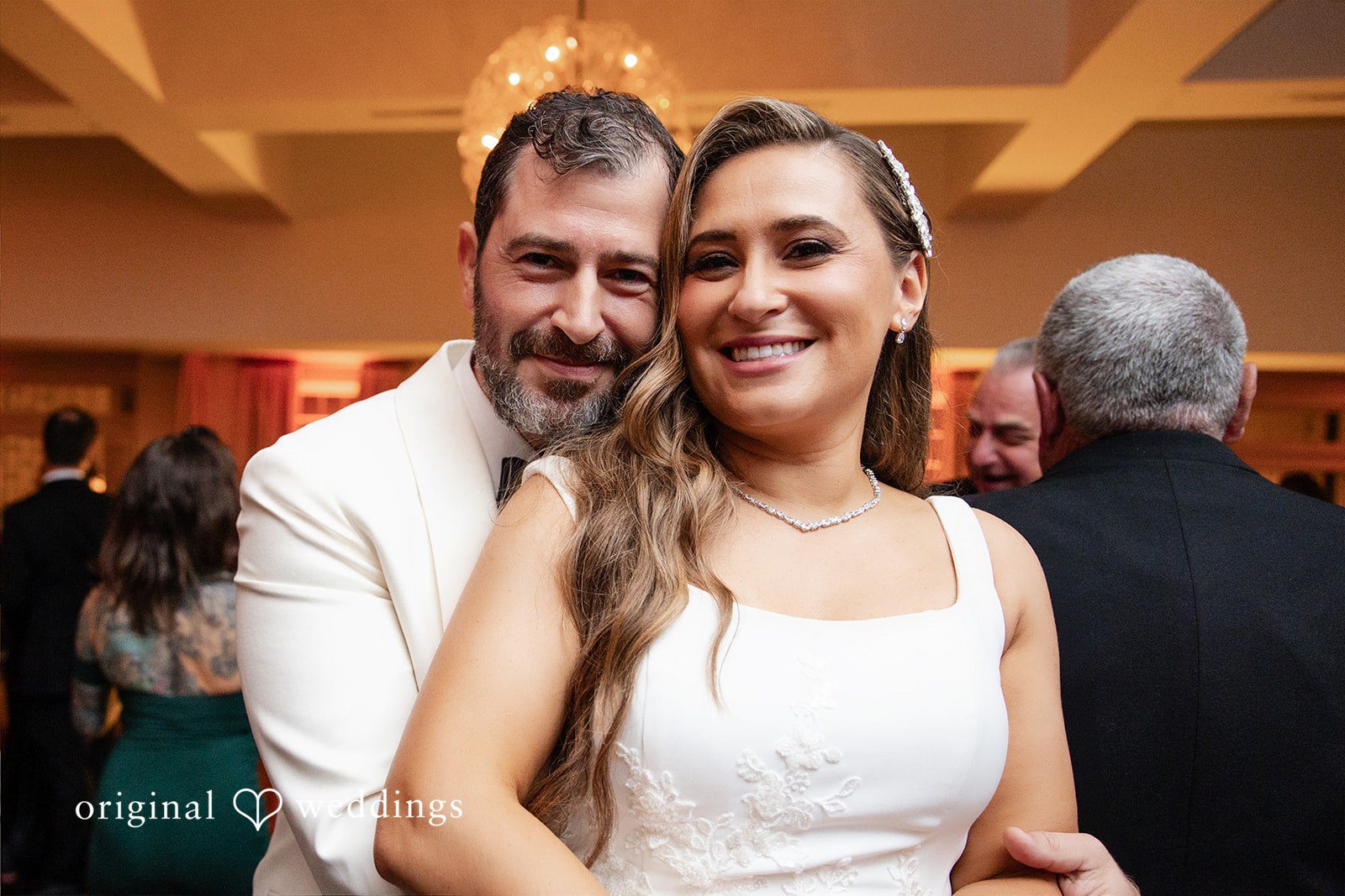 Groom and bride smiling warmly for a close-up portrait together.