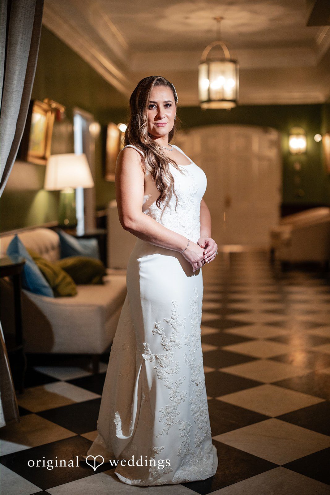 Bride in her wedding gown posing on a checkered floor hallway.