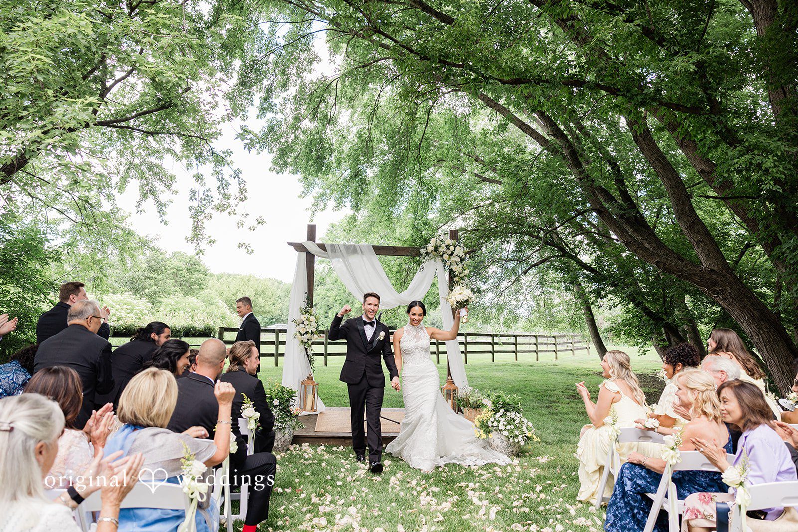 Chicago Wedding Photographers capturing couple walking outside after the wedding with their hands raised in celebration at Chicago Backyard by Original Weddings