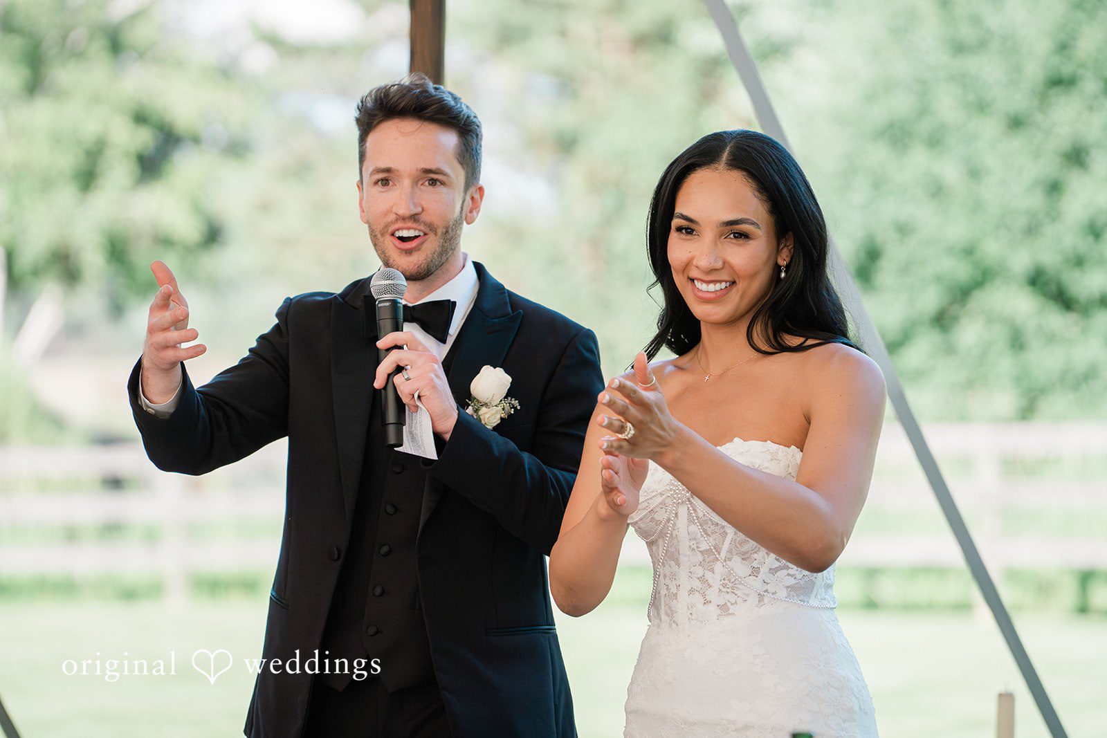 Chicago Wedding Photographers capturing couple standing together  and groom holding a mike while smiling at Chicago Backyard by Original Weddings