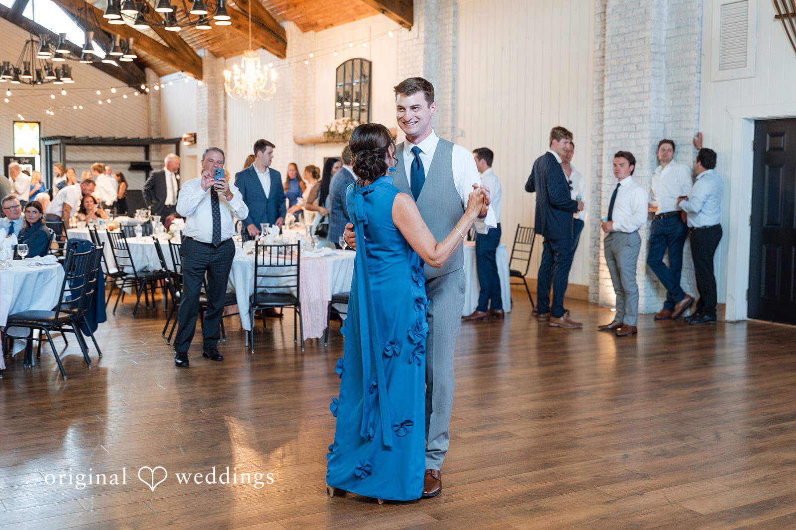 Cassandra + Adam Wedding guest in a blue dress dancing in the middle of the reception floor.