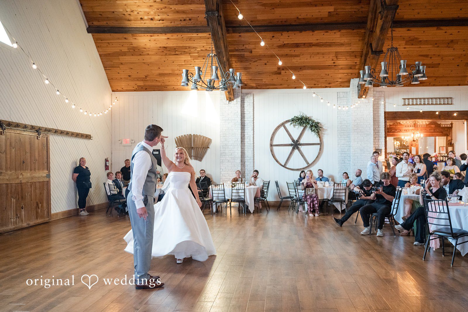 Cassandra + Adam Wide view of the bride and groom dancing on the wooden reception floor.