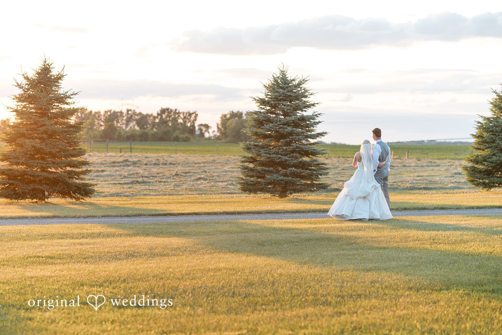 Cassandra + Adam Distant view of the bride standing alone in a wide grassy field.