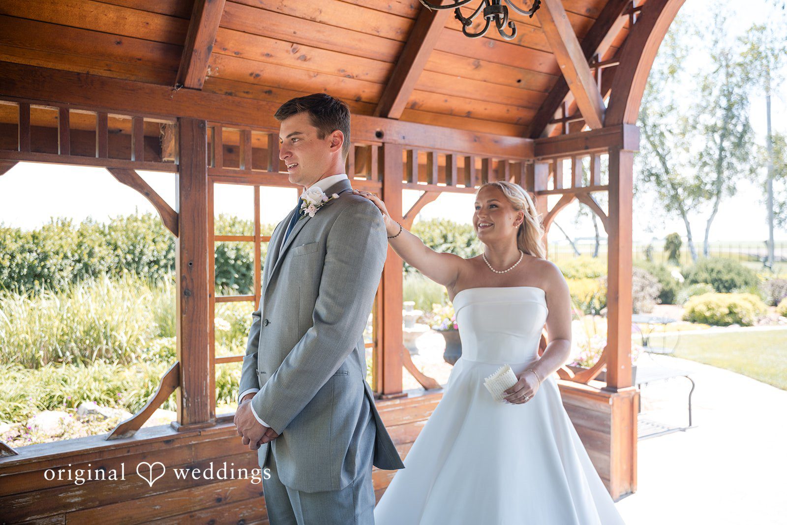 Cassandra + Adam Bride and groom standing together next to a wooden structure.