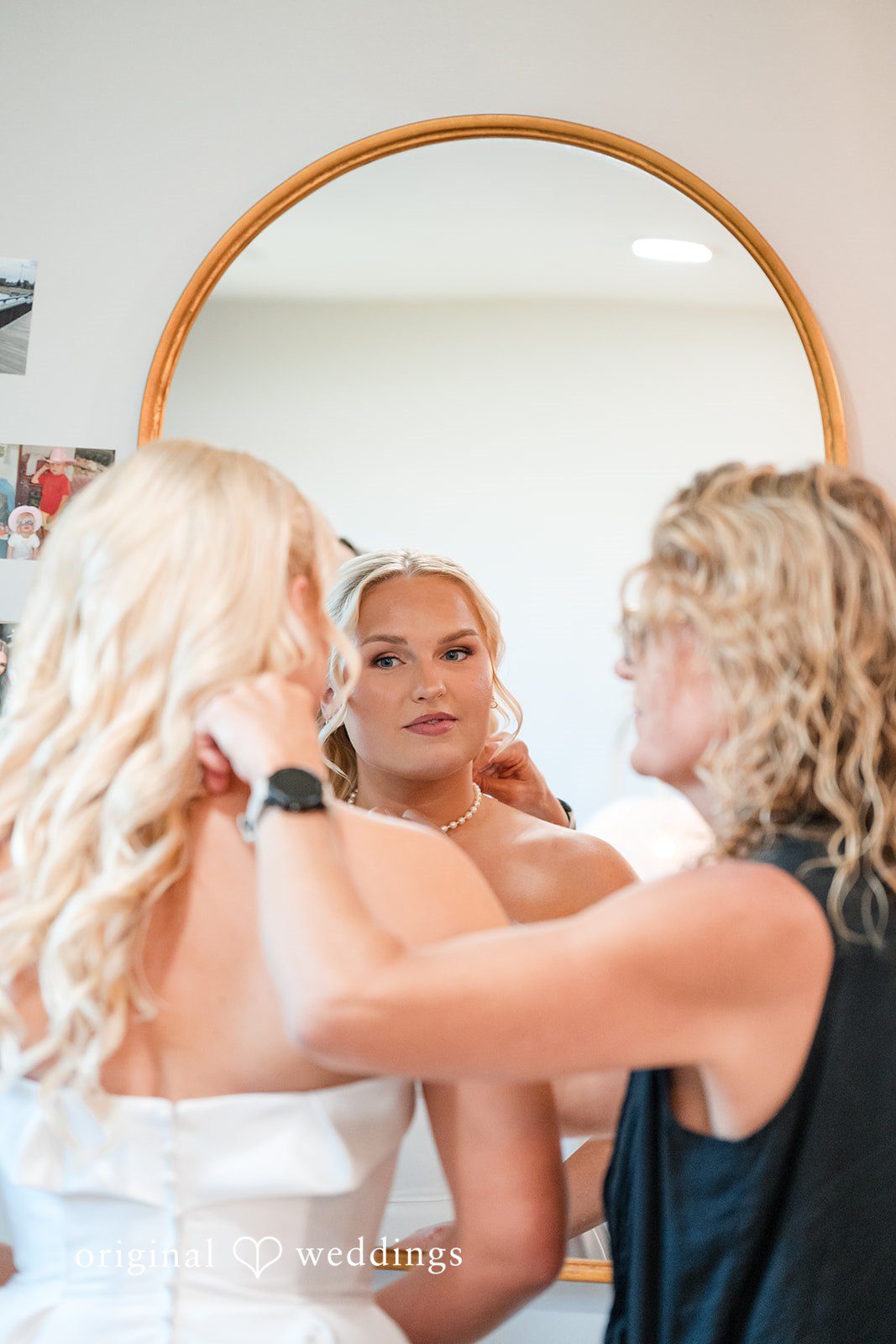 Cassandra + Adam Bride looking in a round mirror while being helped into her dress.