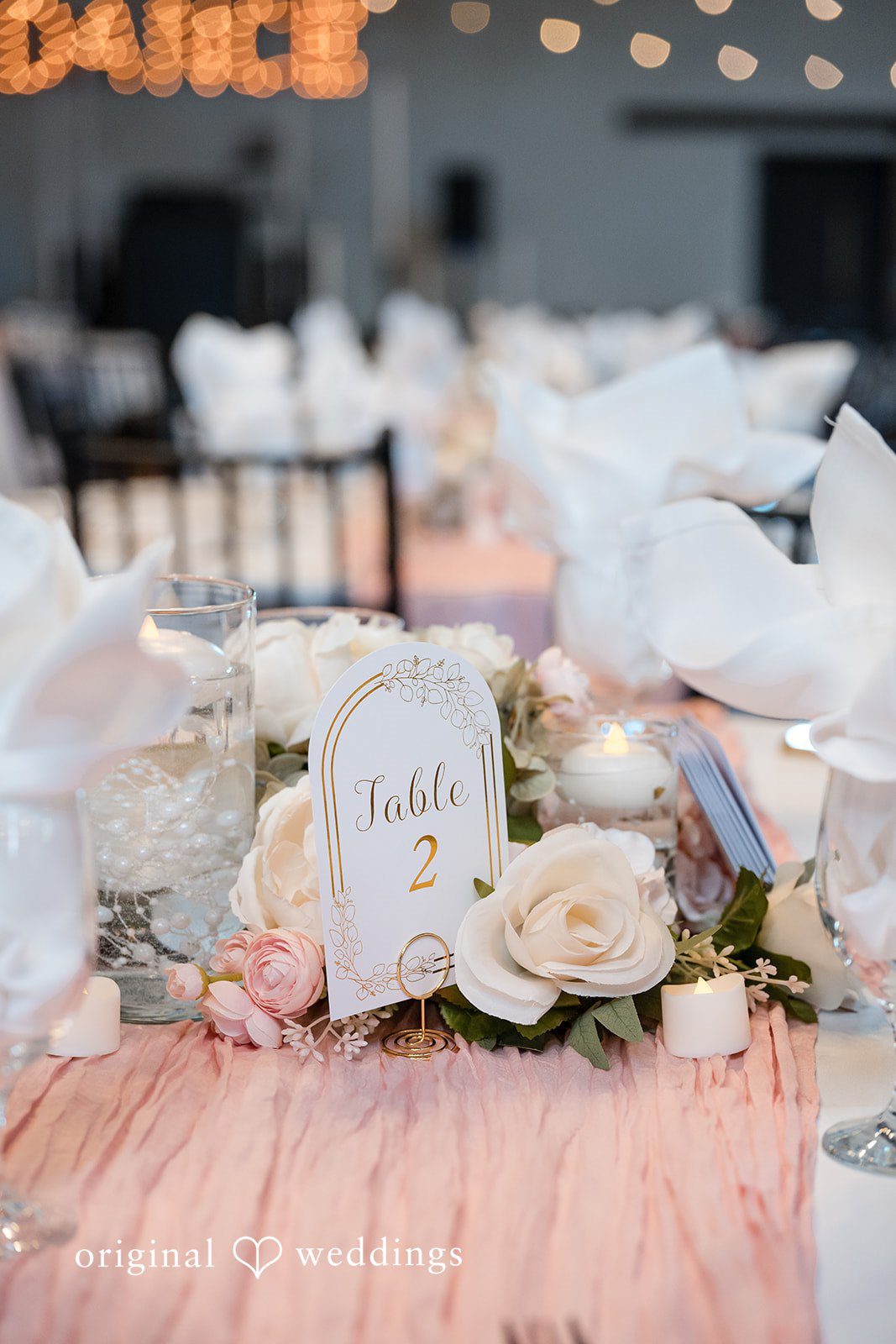 Cassandra + Adam Table centerpiece featuring white roses, candles, and a pink runner.