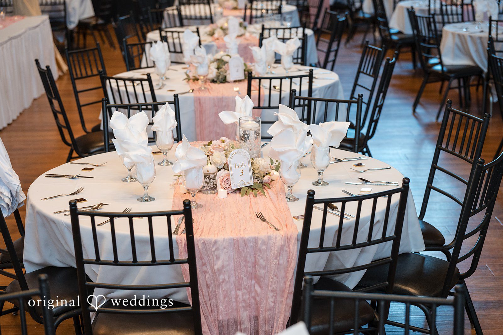 Cassandra + Adam Round reception table set with black chairs and a pink fabric runner.