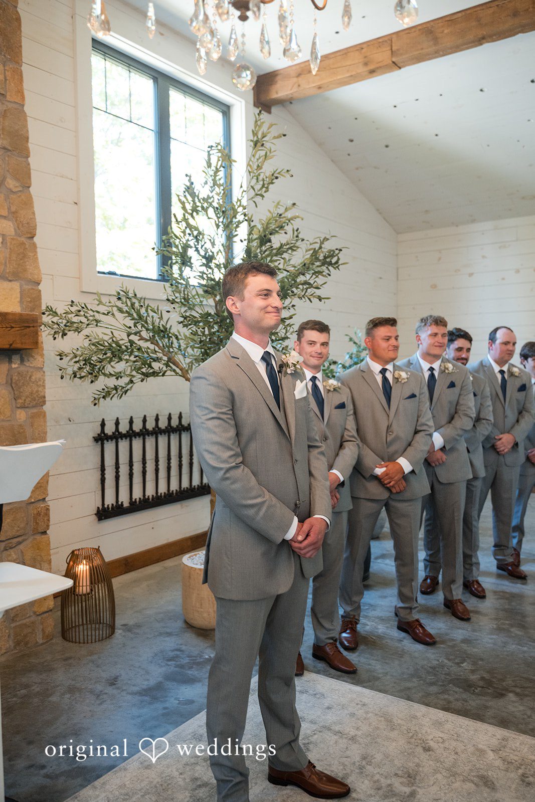 Cassandra + Adam Groom and his groomsmen standing in a lined formation inside a venue.
