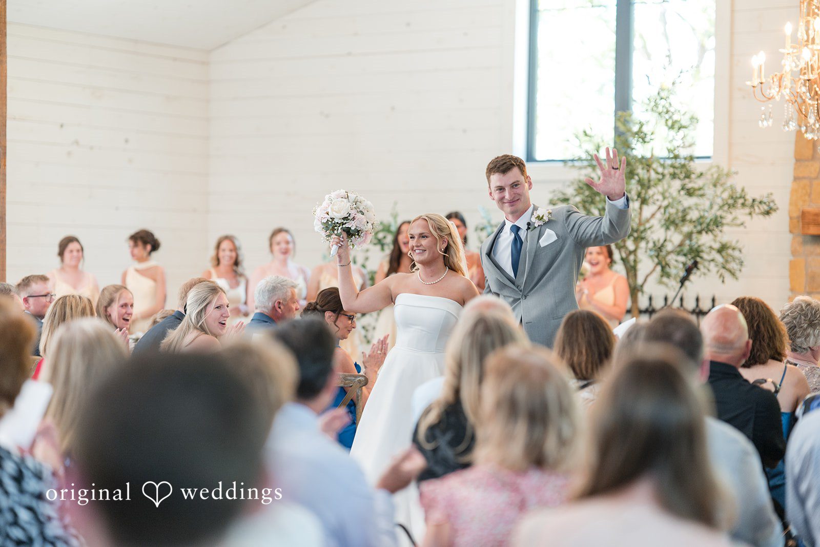 Cassandra + Adam Bride and groom cheering with hands raised at the altar facing guests.