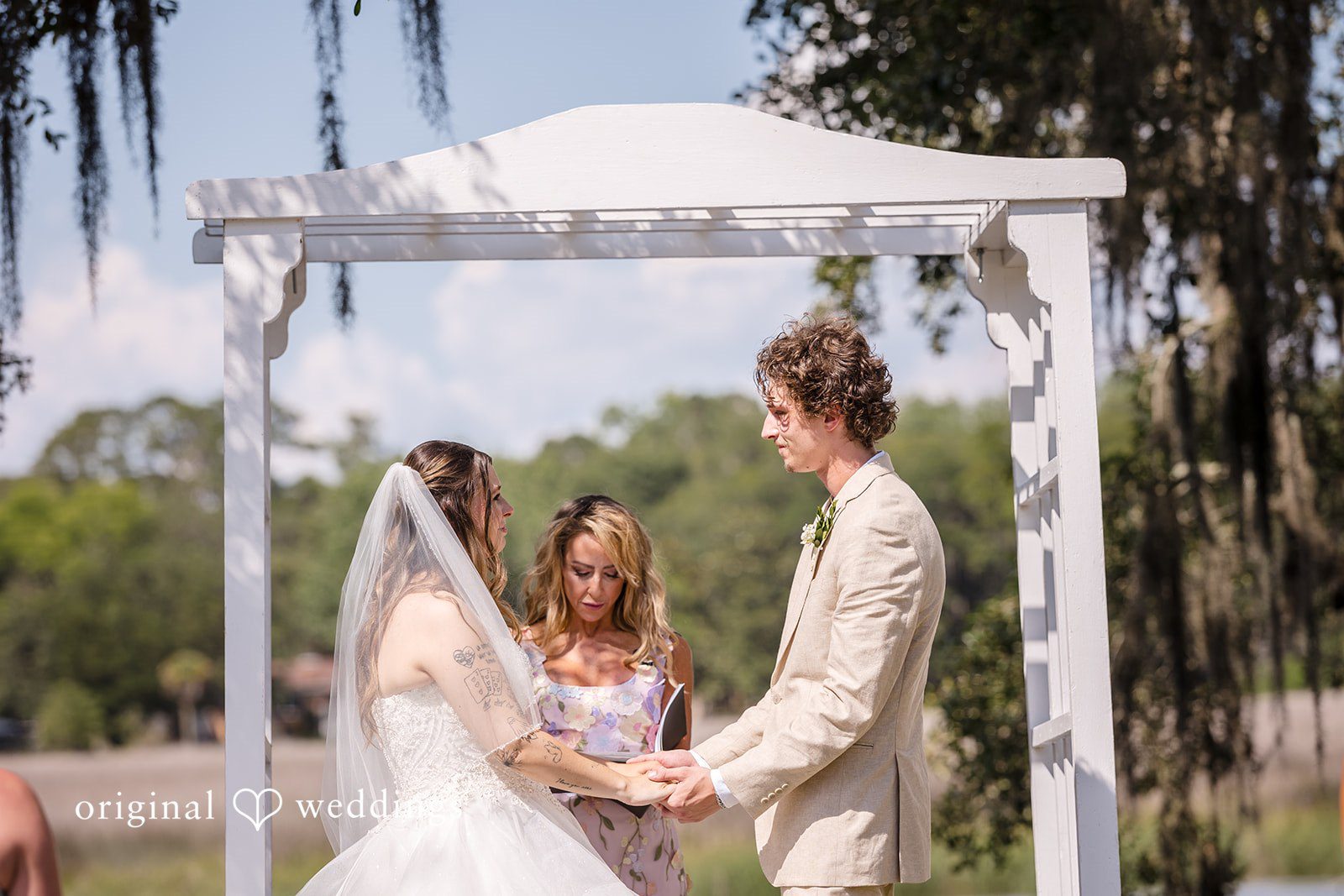 Madison + Aiden Bride and groom holding hands during their ceremony at Magnolia Plantation and Gardens captured by Charleston Wedding Photographers from Original Weddings